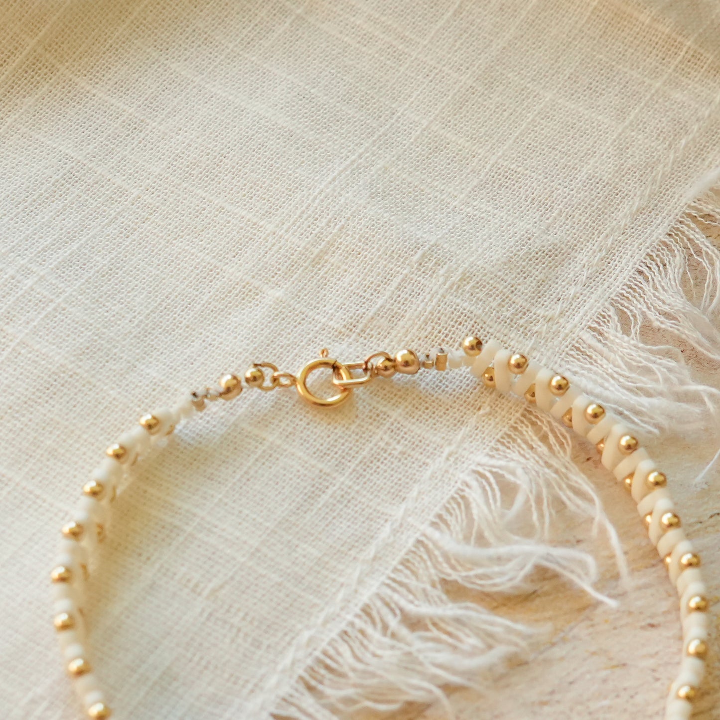 bracelet with white Japanese glass and gold-fill ball beads on a white cloth