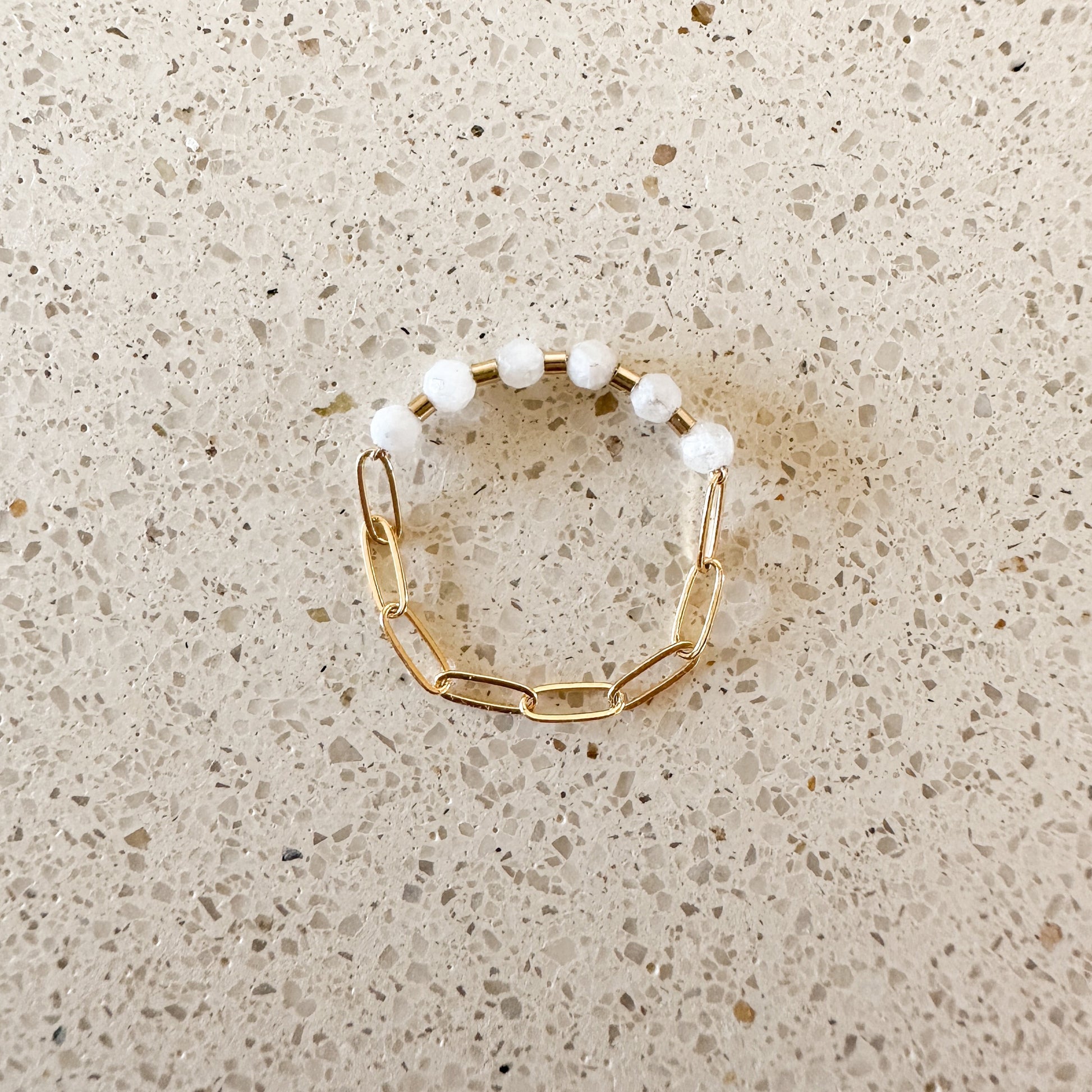 ring with white moonstone faceted quartz stones and gold-filled chain on a quartz countertop