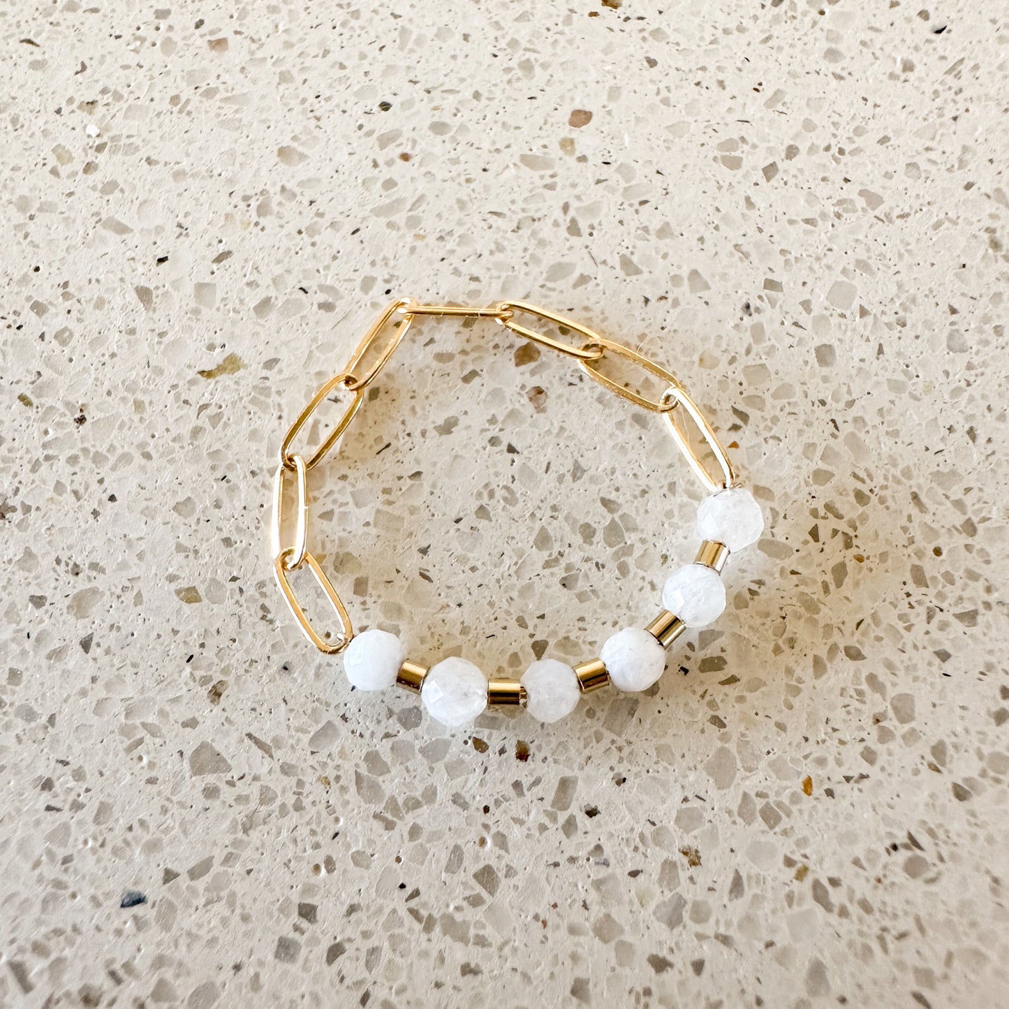 ring with white moonstone faceted quartz stones and gold-filled chain on a quartz countertop