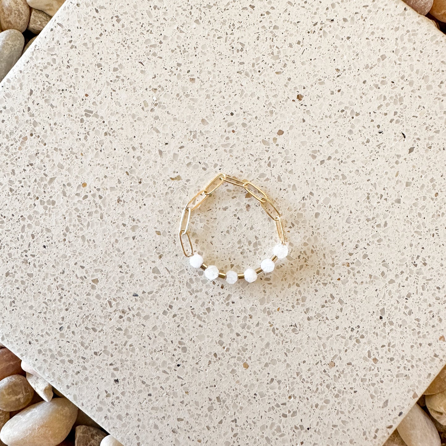 ring with white moonstone faceted quartz stones and gold-filled chain on a quartz countertop