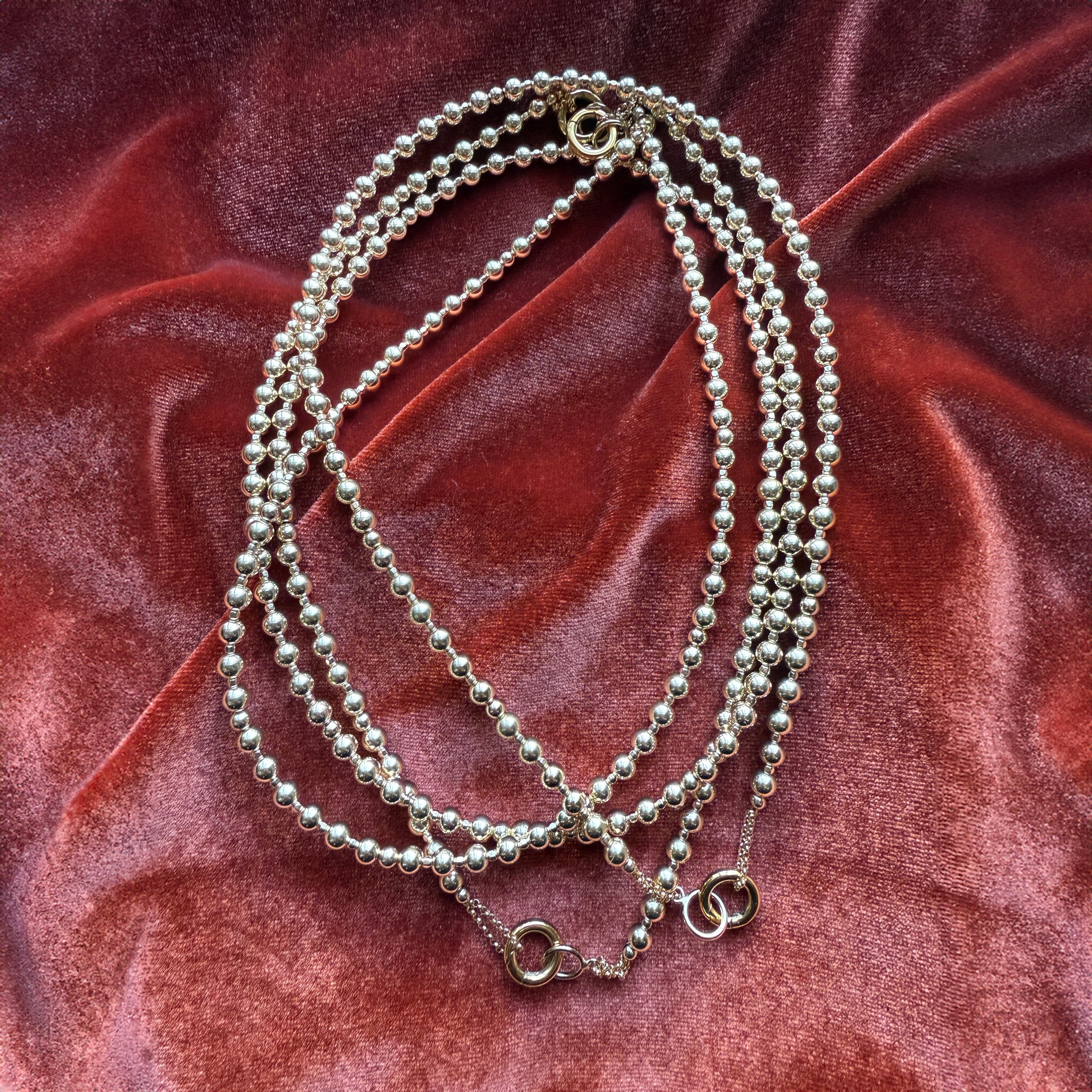 aerial view of a bundle of gold-filled beaded necklaces on a red cloth