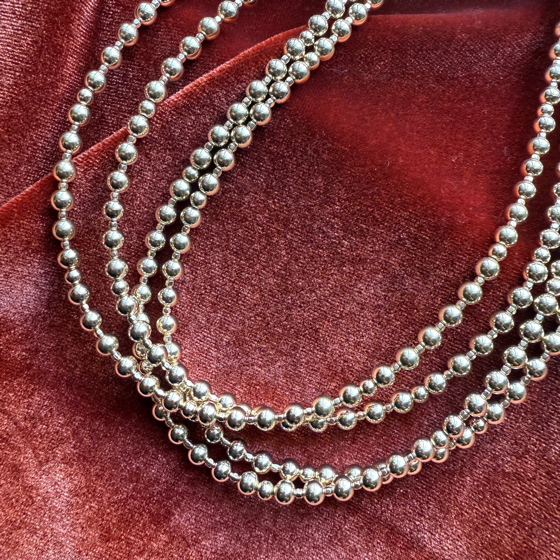 group of gold-filled beaded necklaces on red cloth