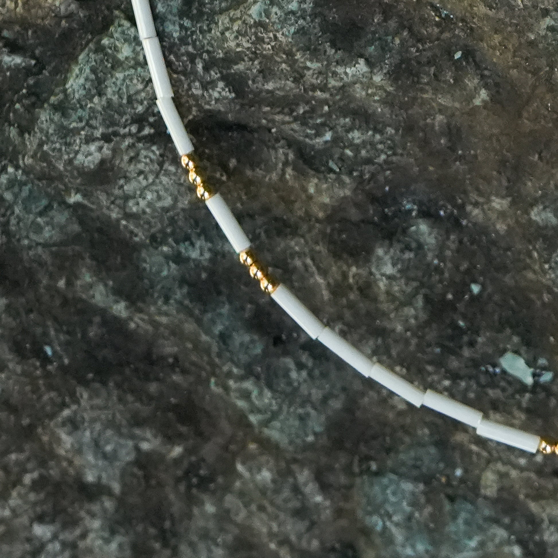 close up view of white beaded bracelet with gold bead accents