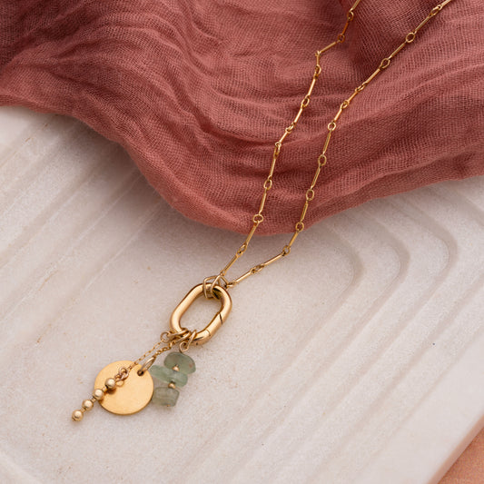 gold-filled necklace with raw Ecuadorian jade stones and gold charms on a marble tray