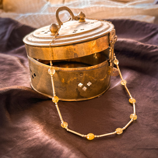gold-filled and citrine beaded necklace on a vintage brass container