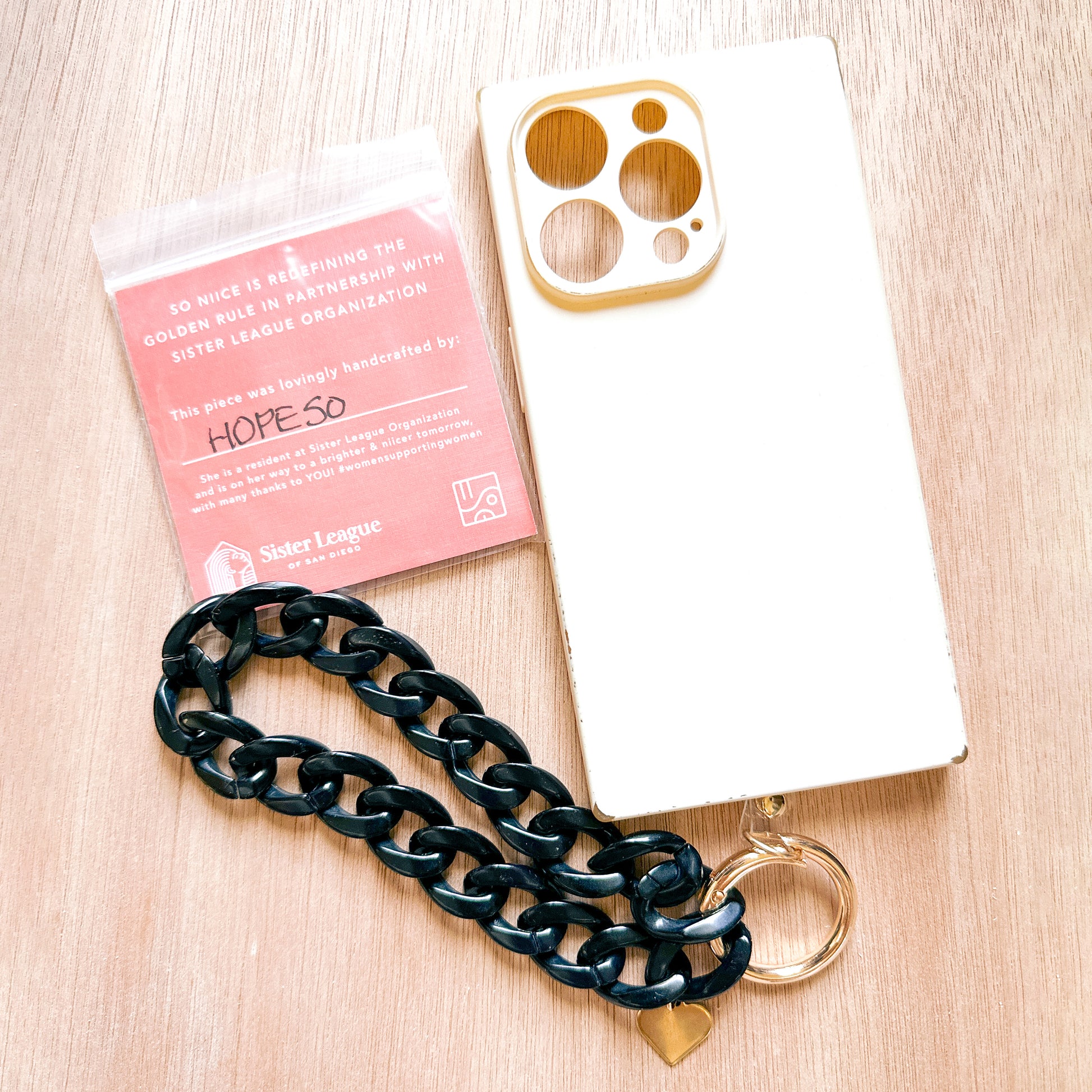 black acrylic link phone bracelet tethered to a phone case next to a Sister League tag