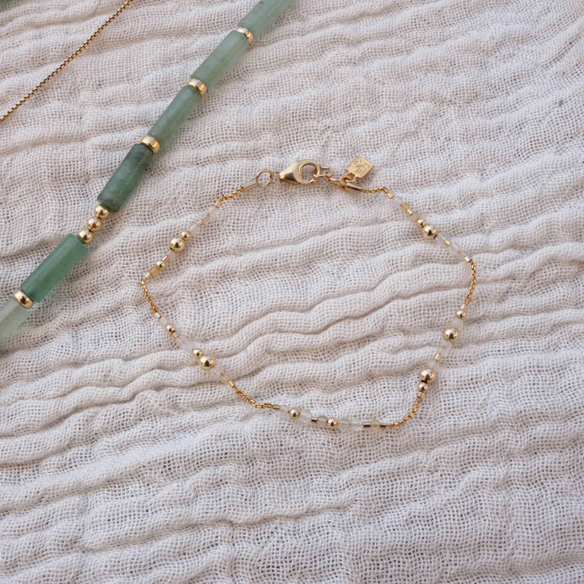 clasped bracelet with citrine and gold-filled beads next to a necklace with aventurine beads