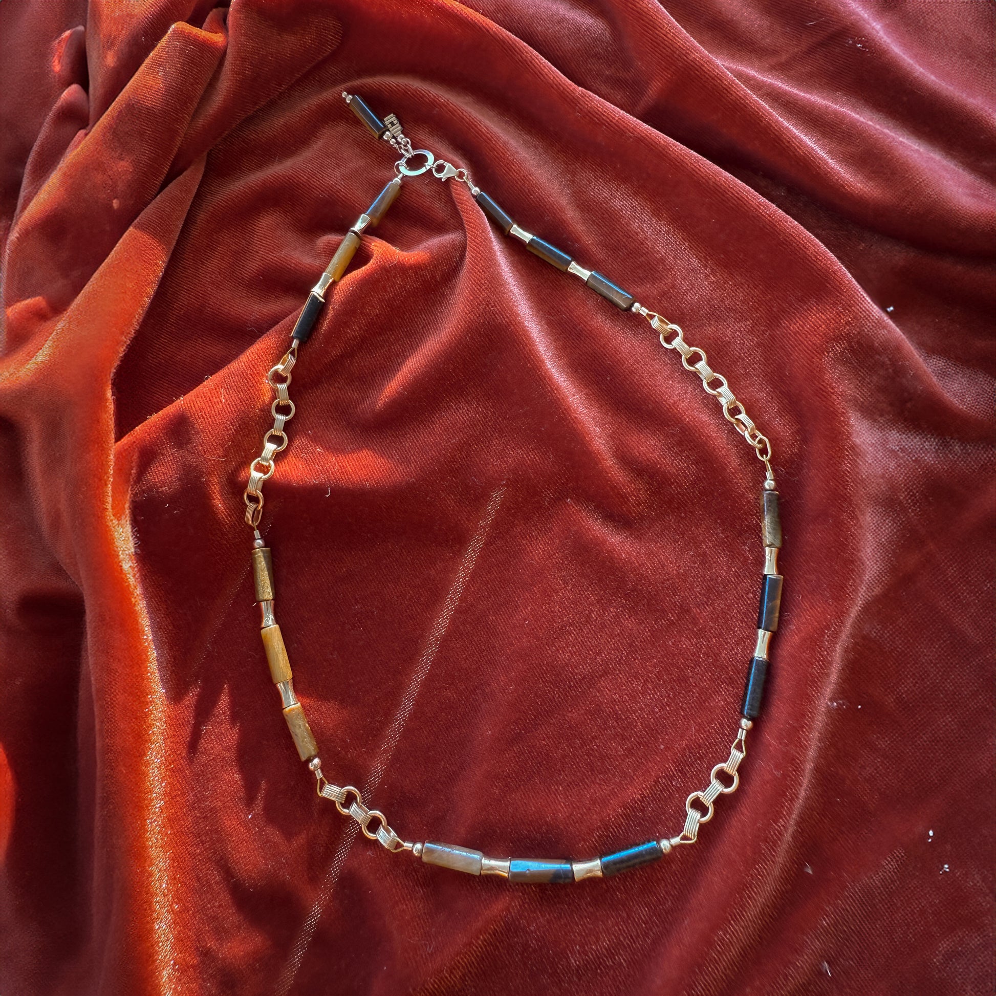 necklace with tiger's eye beads, gold-filled beads, and gold links on a red cloth