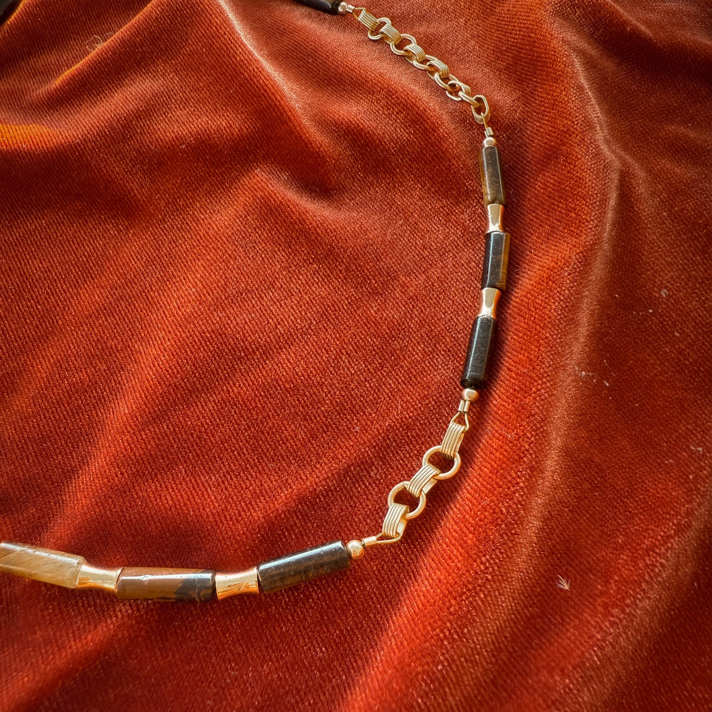 close up view of gold links, tiger's eye beads bamboo-shaped, and tubular gold-filled beads on a necklace