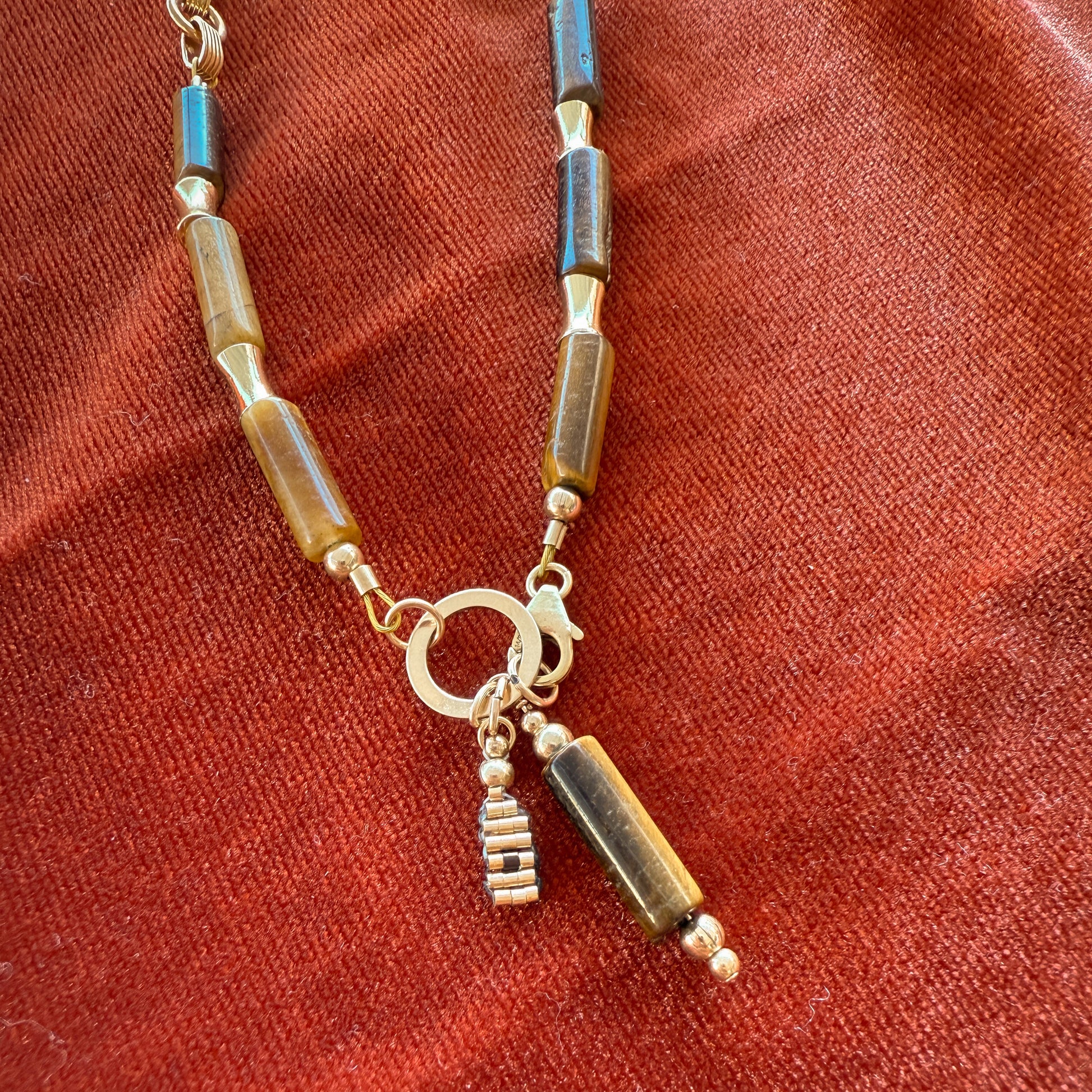 close up view of a stylish clasp with a large gold ring and dangling beaded accents on a necklace