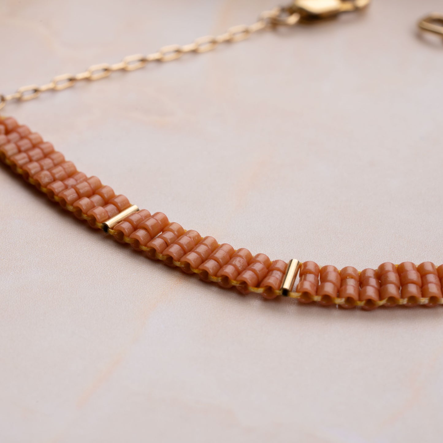 close up view of coral-colored glass bead pattern on a bracelet