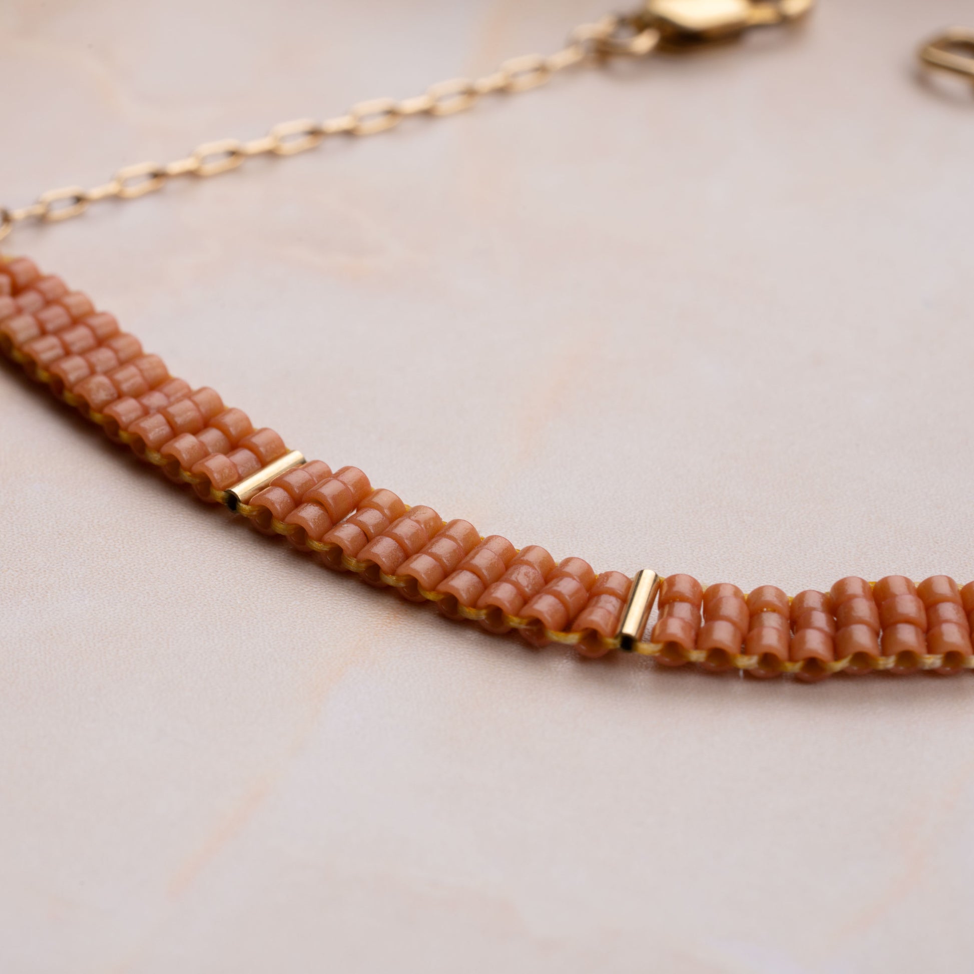 close up view of coral-colored glass bead pattern on a bracelet