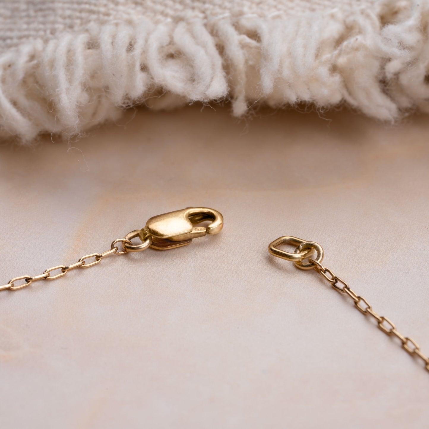 gold clasp with a chain and a white blanket in the background
