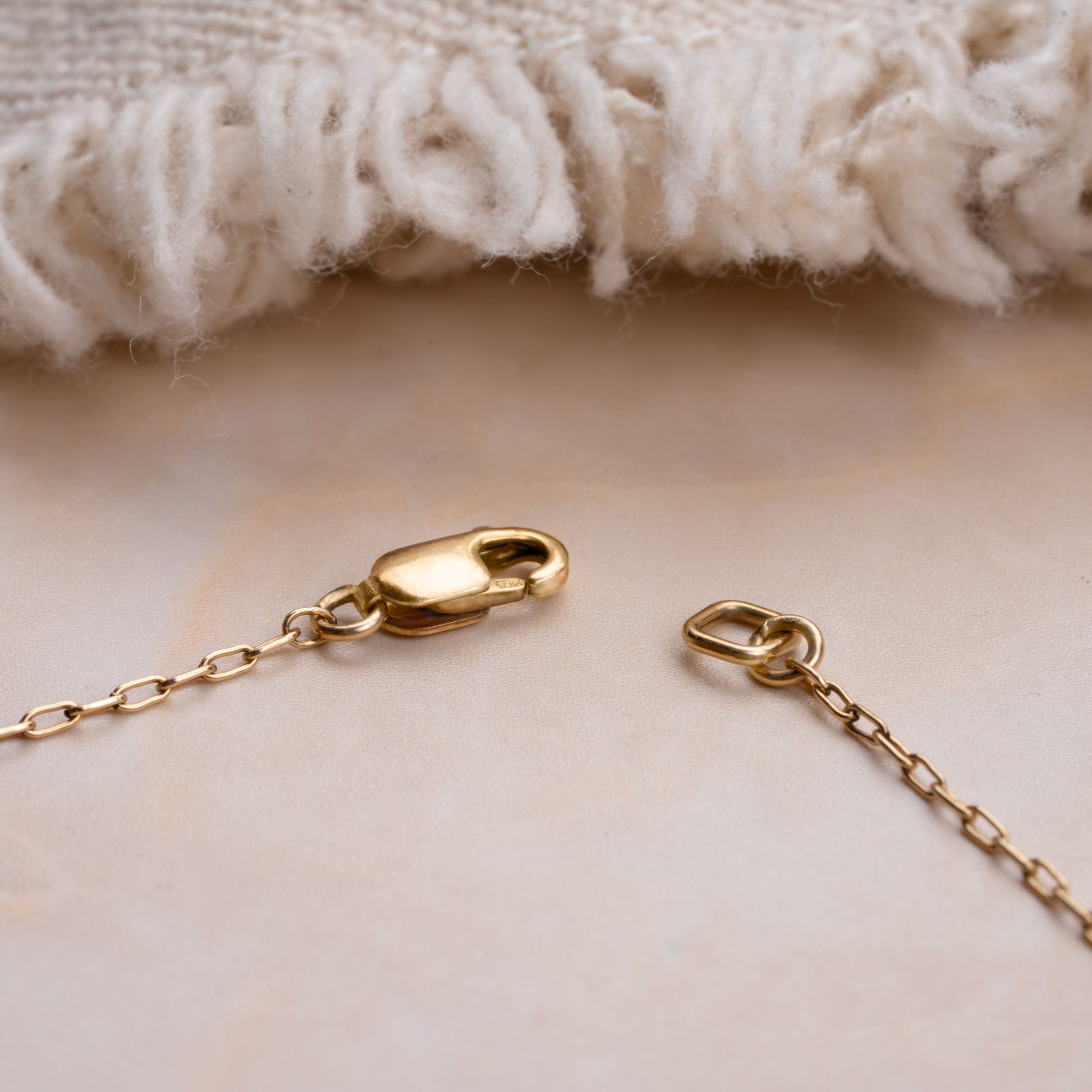 gold clasp with a chain and a white blanket in the background