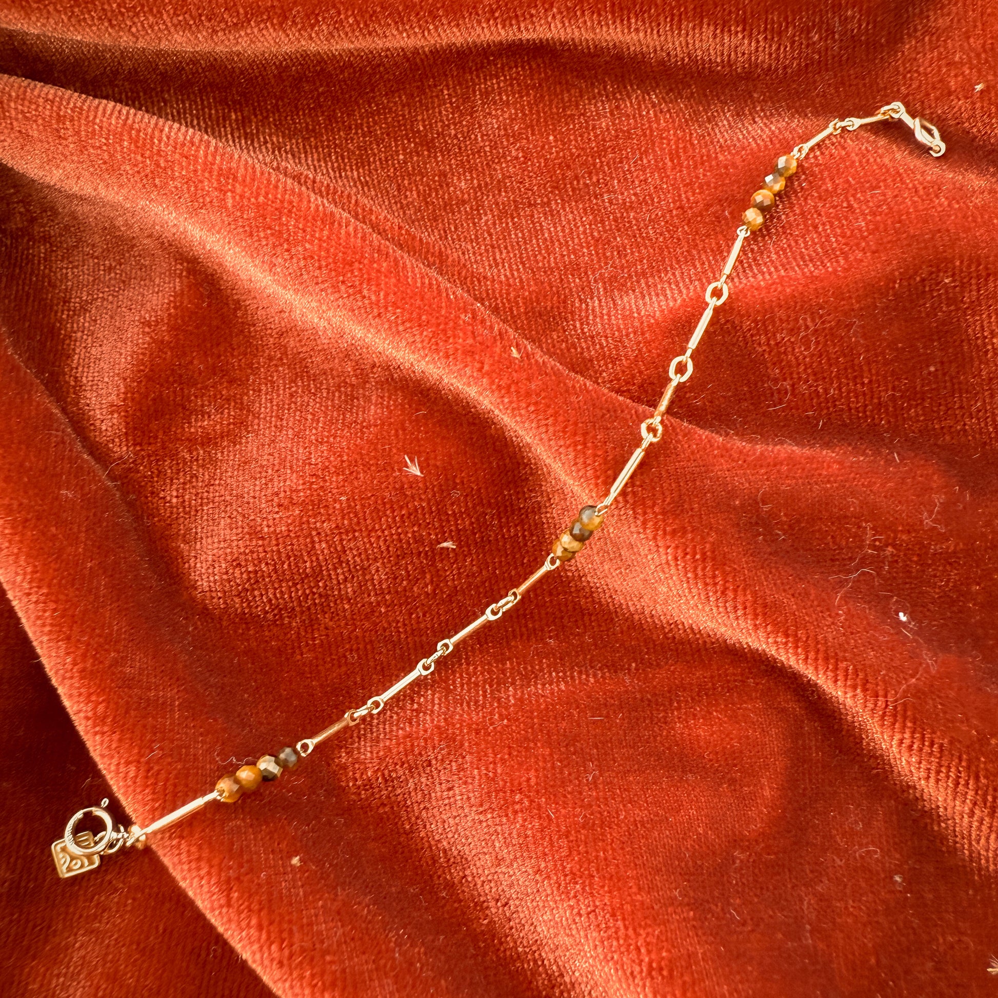 unclasped bracelet with tiger's eye and gold-filled beads on a red cloth