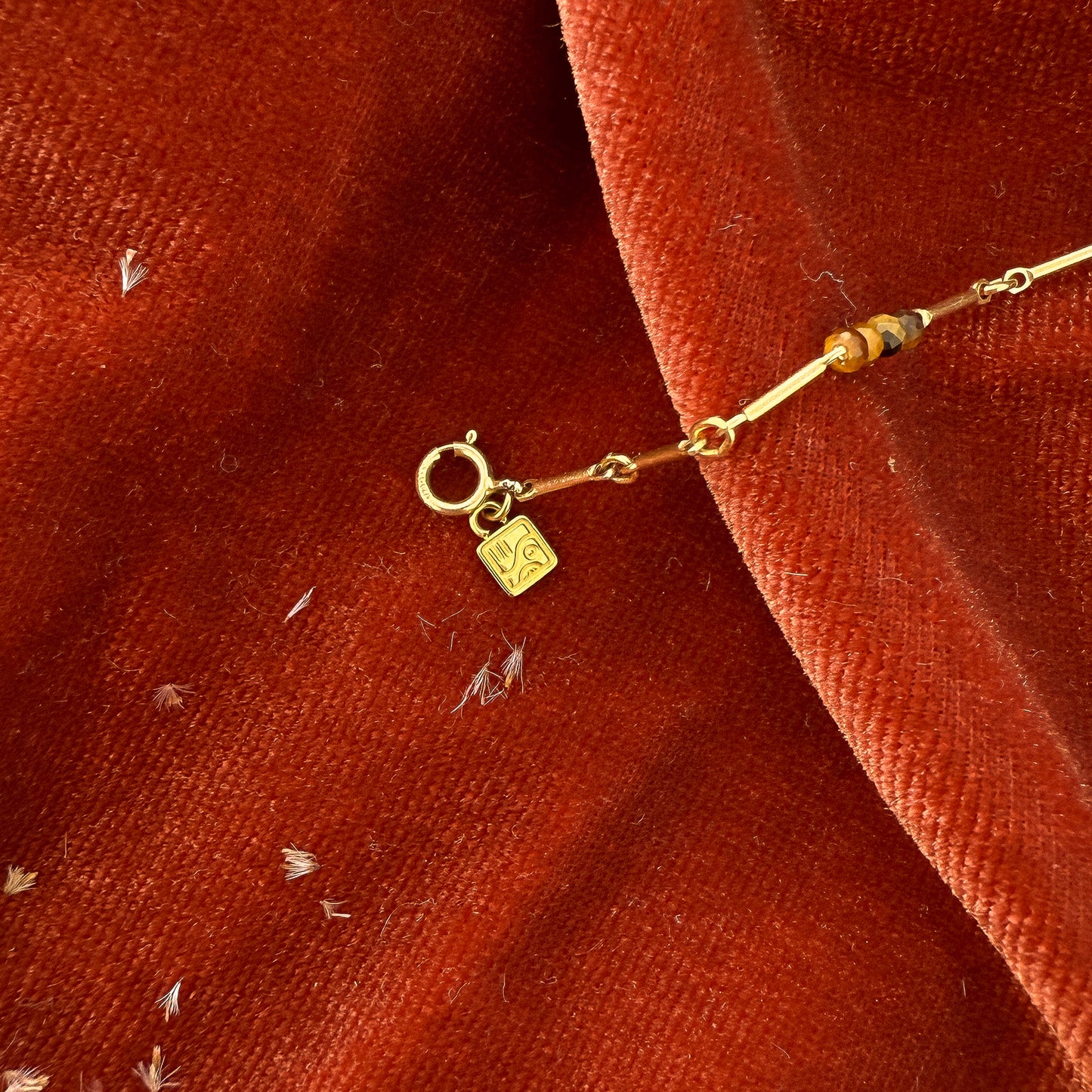 close up view of clasp with a So Niice logo charm and tiger's eye beads on a bracelet