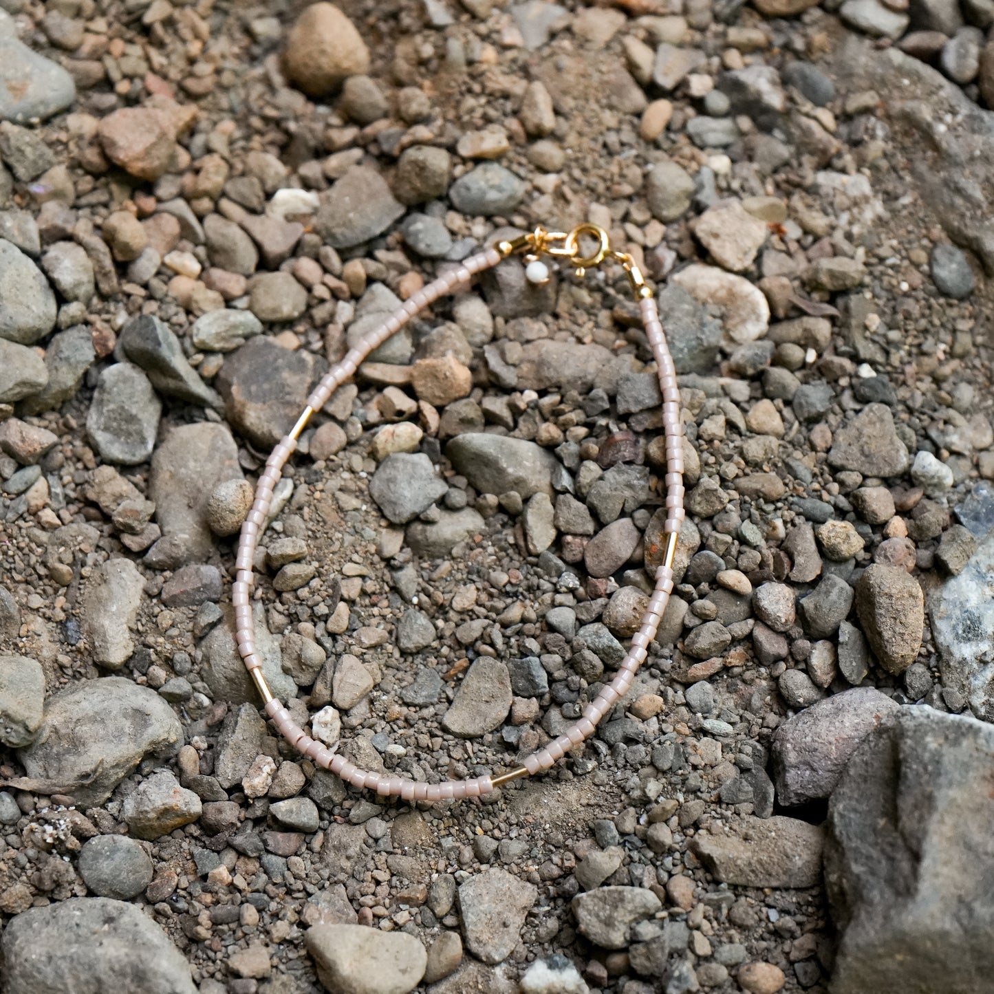 dainty bracelet with Japanese glass seed beads and an Australian opal accent on dirt and rocks