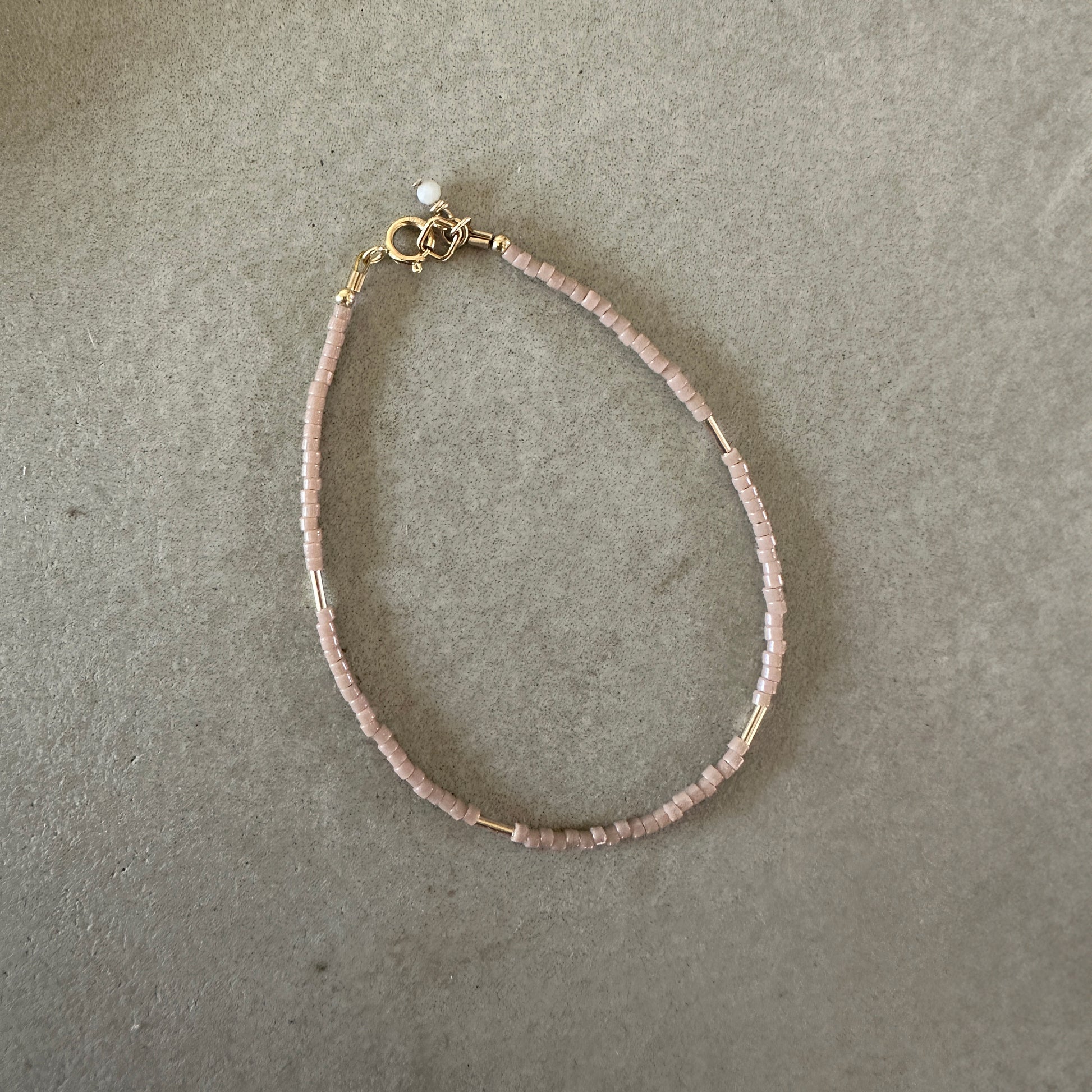 Japanese seed bead bracelet with Australian opal accent laying on a cement surface