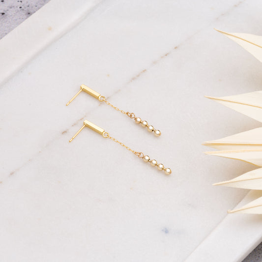 gold-filled dangling beaded earrings on a marble tray