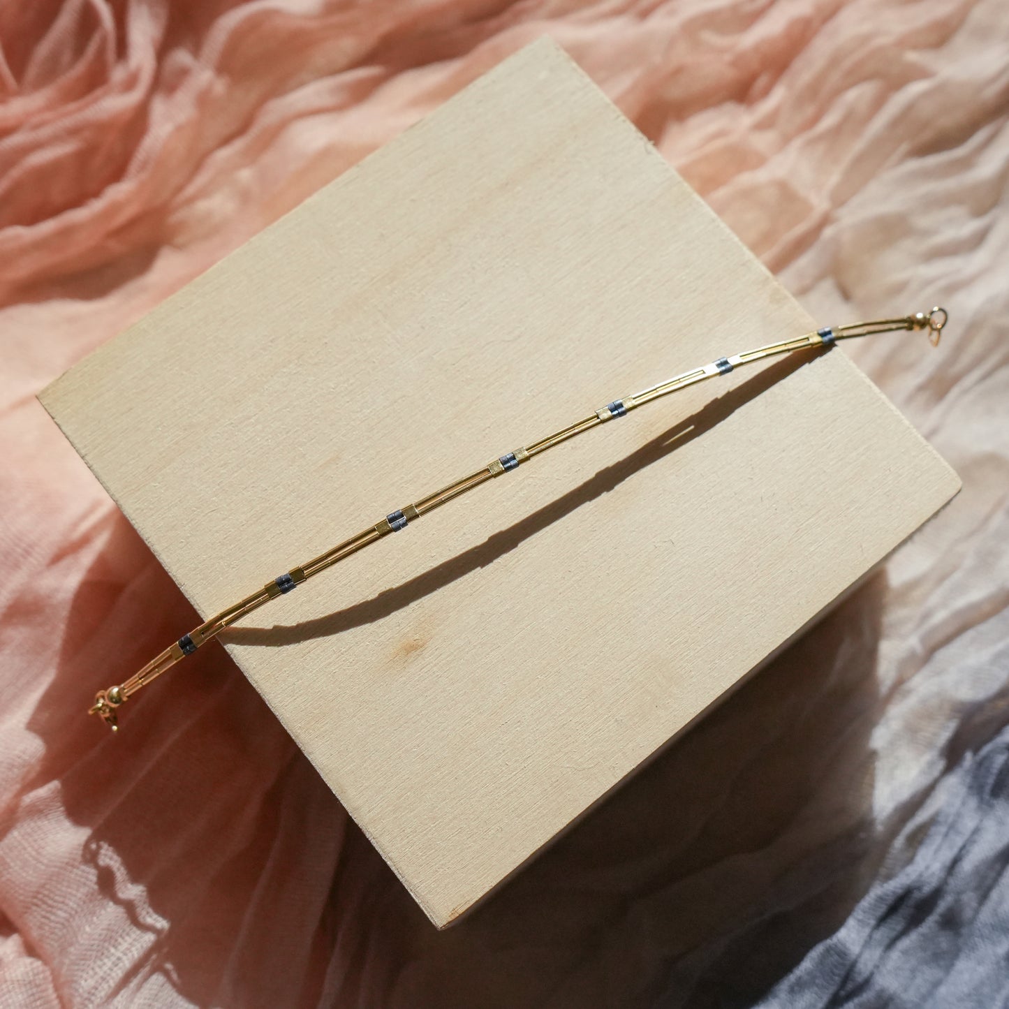 gold-fill beaded bracelet opened on a wooden block