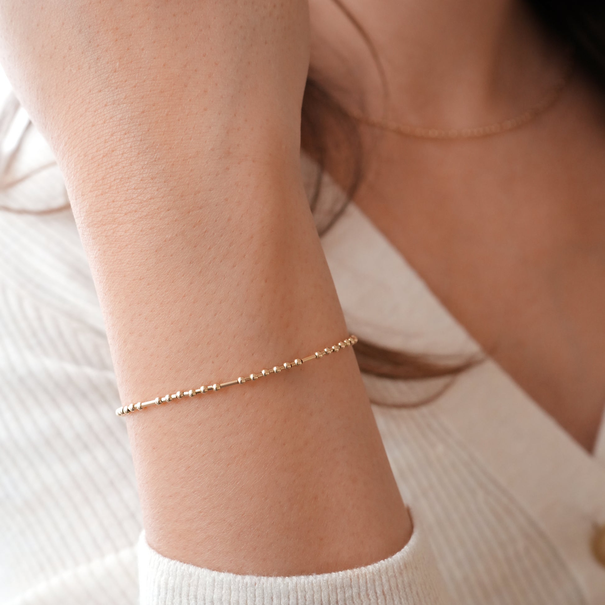 woman's wrist wearing gold fill bead bracelet with ball and tube beads