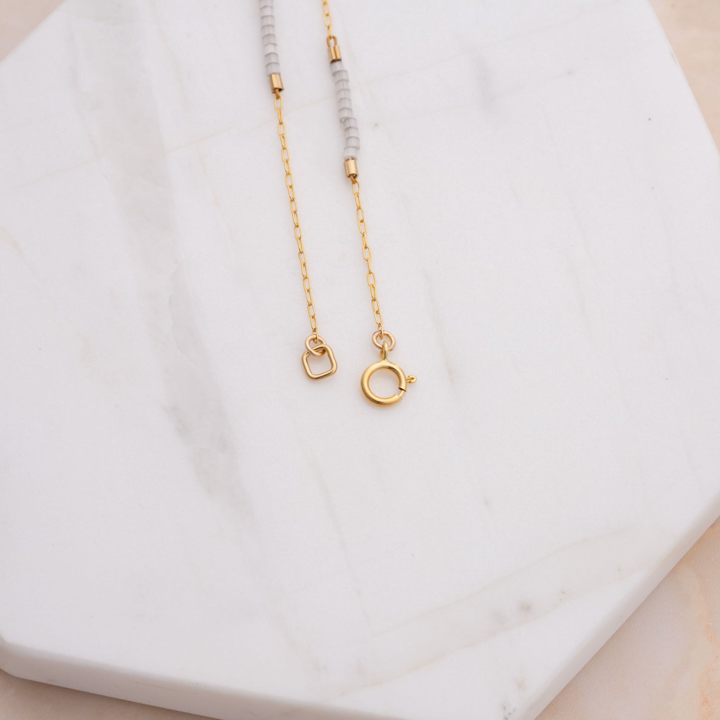 clasp of a bracelet with gold-fill chain and white beads