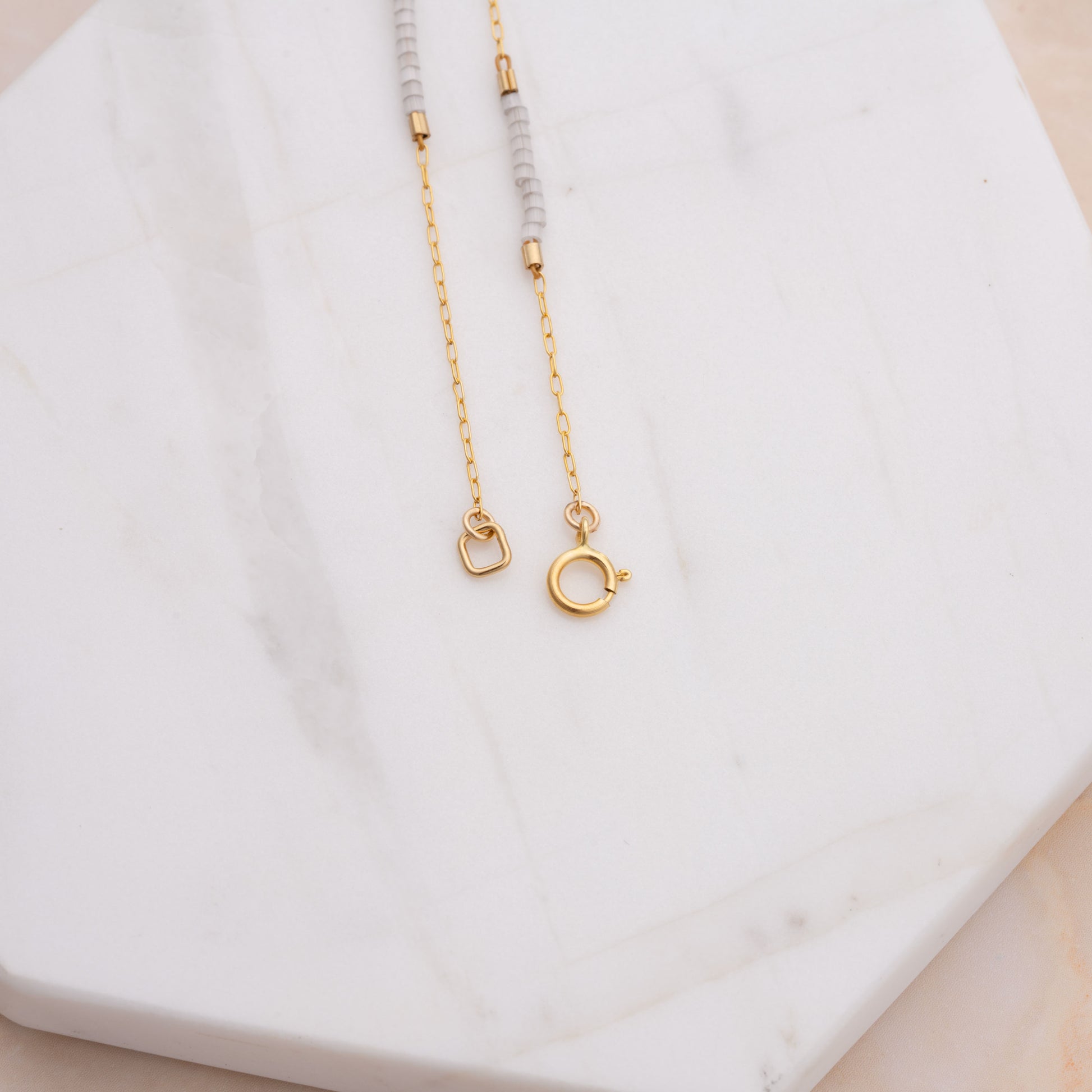 clasp of a bracelet with gold-fill chain and white beads