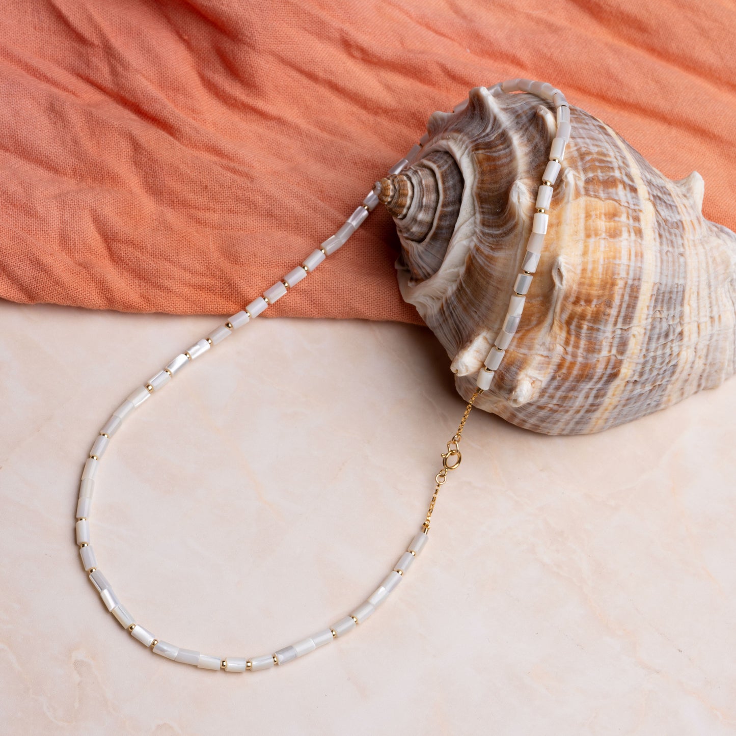 necklace with mother of pearl tube beads resting on a seashell