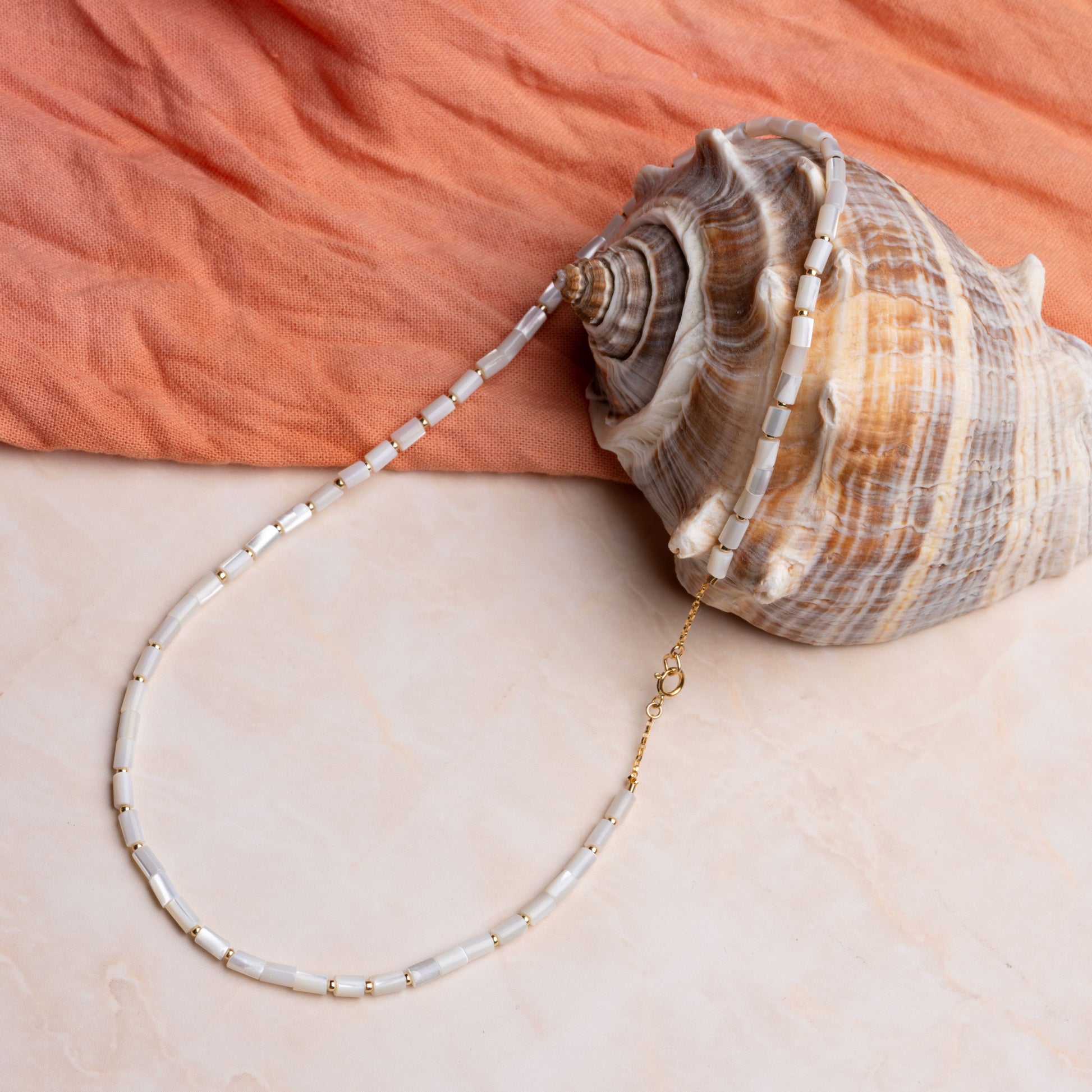 necklace with mother of pearl tube beads resting on a seashell