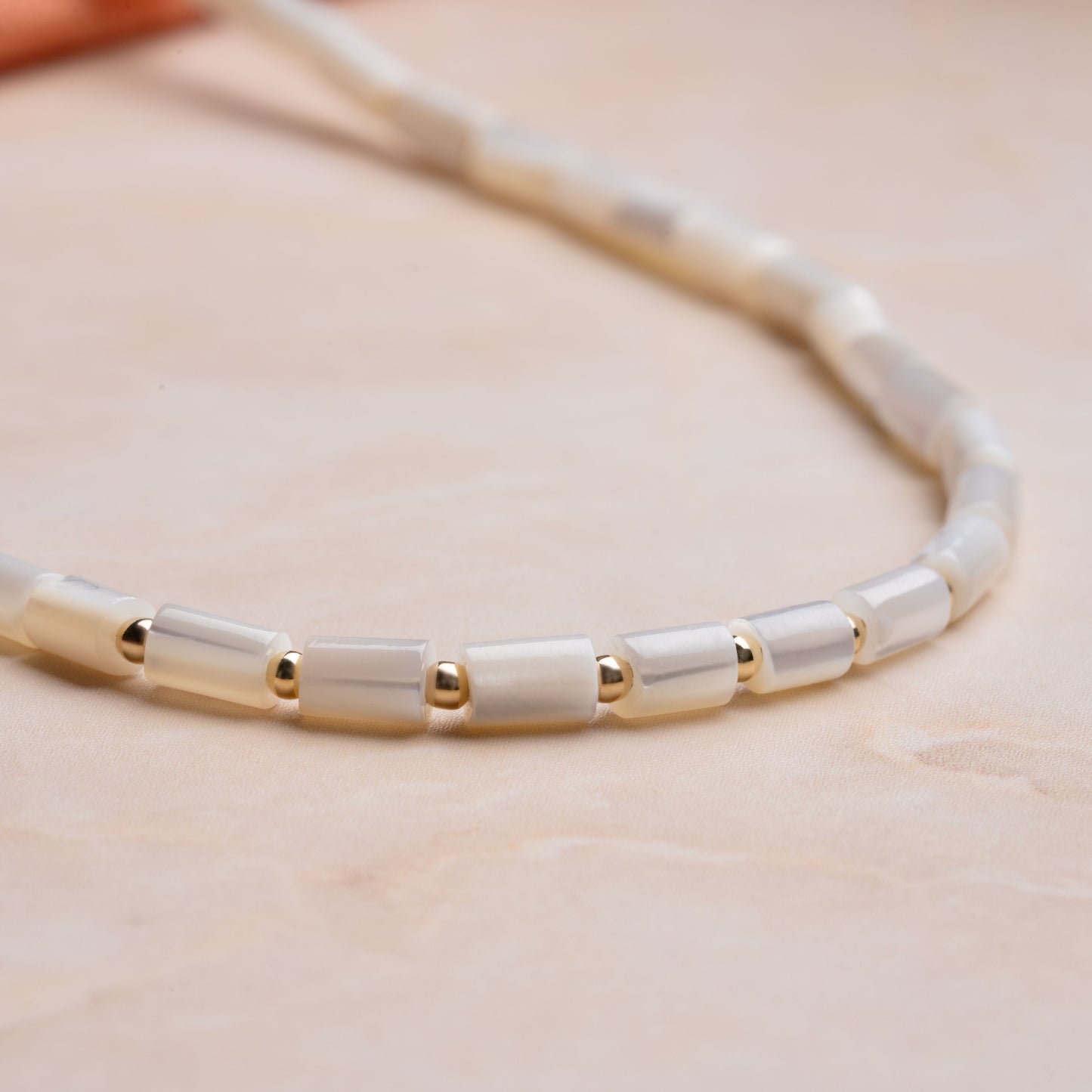 close up view of mother of pearl tube beads and gold-fill ball beads on a necklace