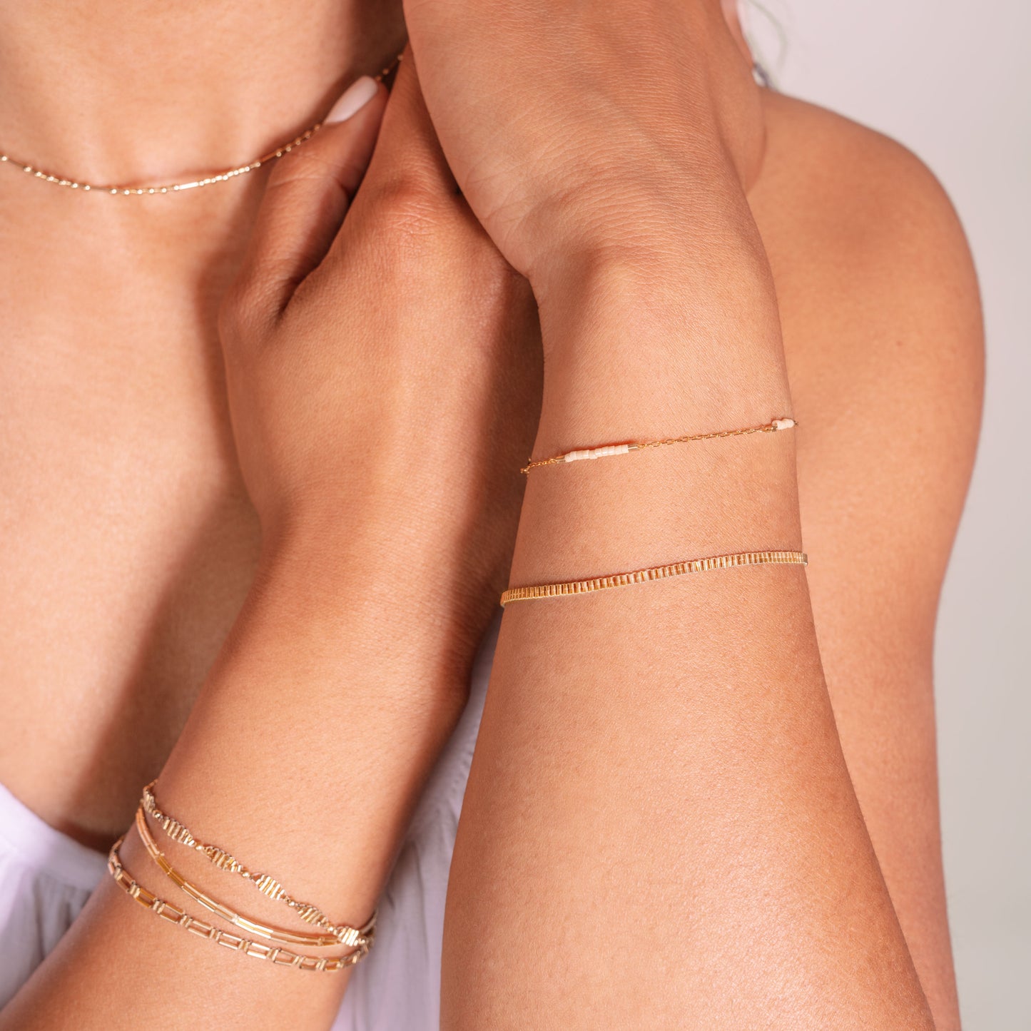 woman wearing stacked gold-fill beaded bracelets on both wrists and a gold-fill beaded necklace