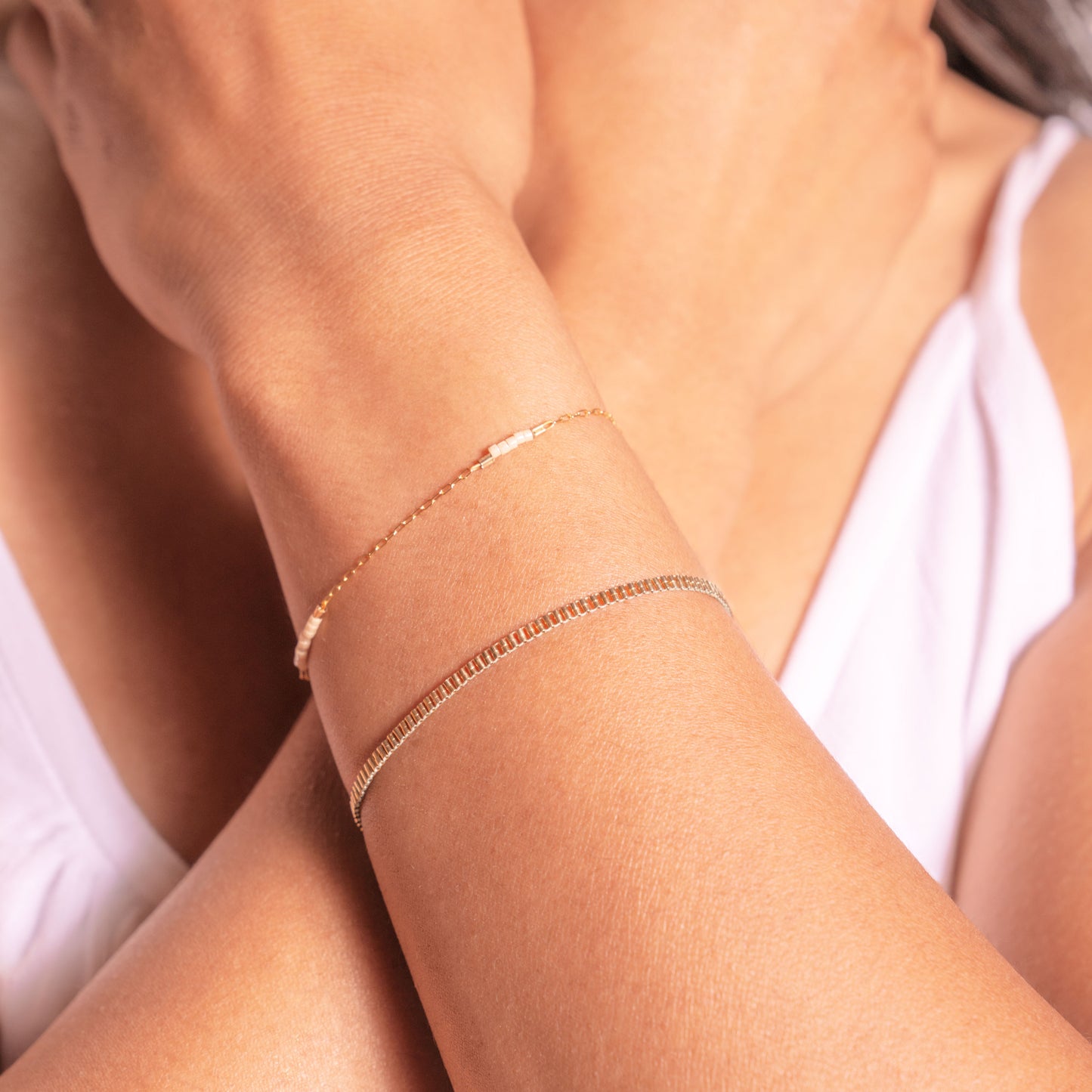 woman wearing two gold-fill and beaded bracelets