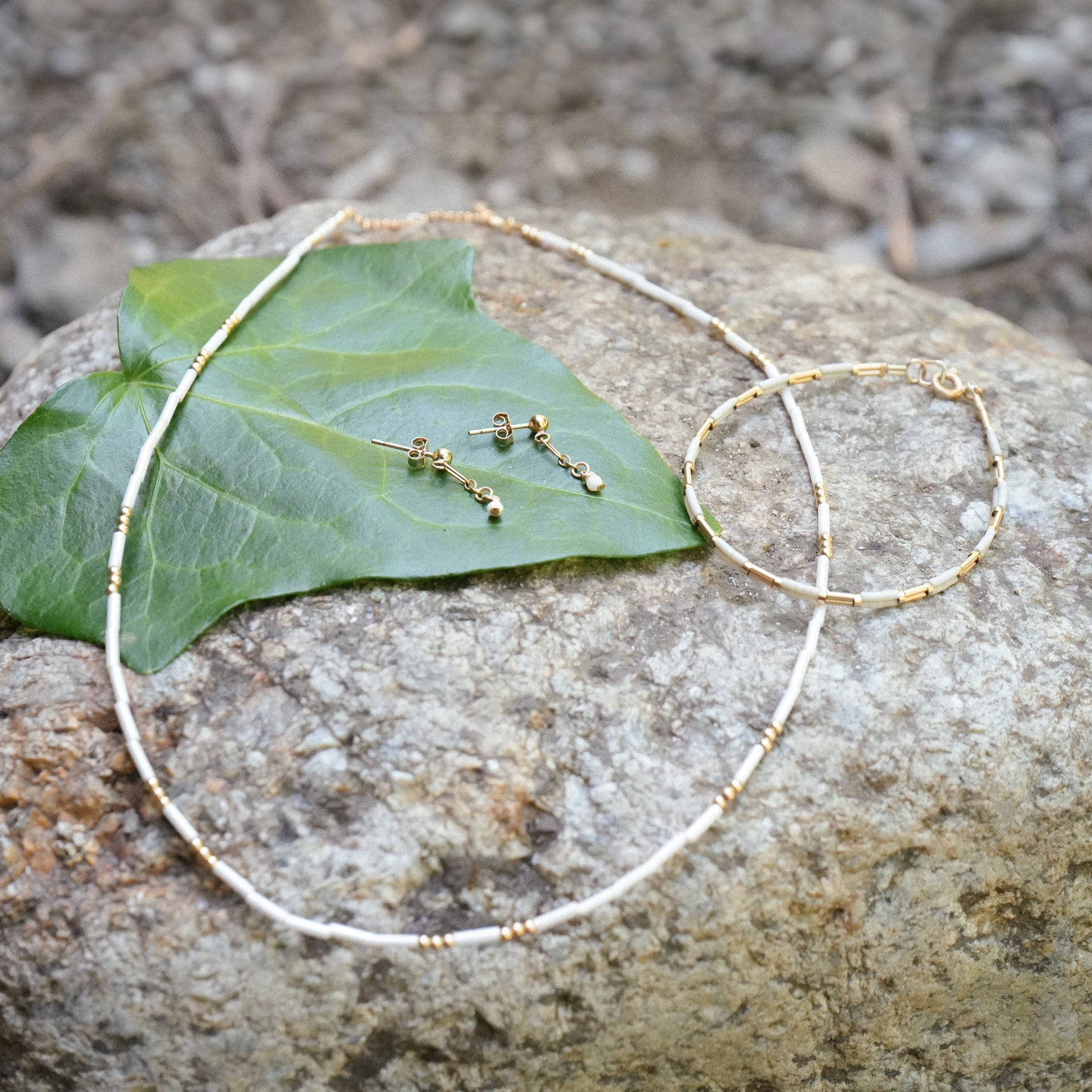 earrings, necklace, and bracelet on a rock and leaf