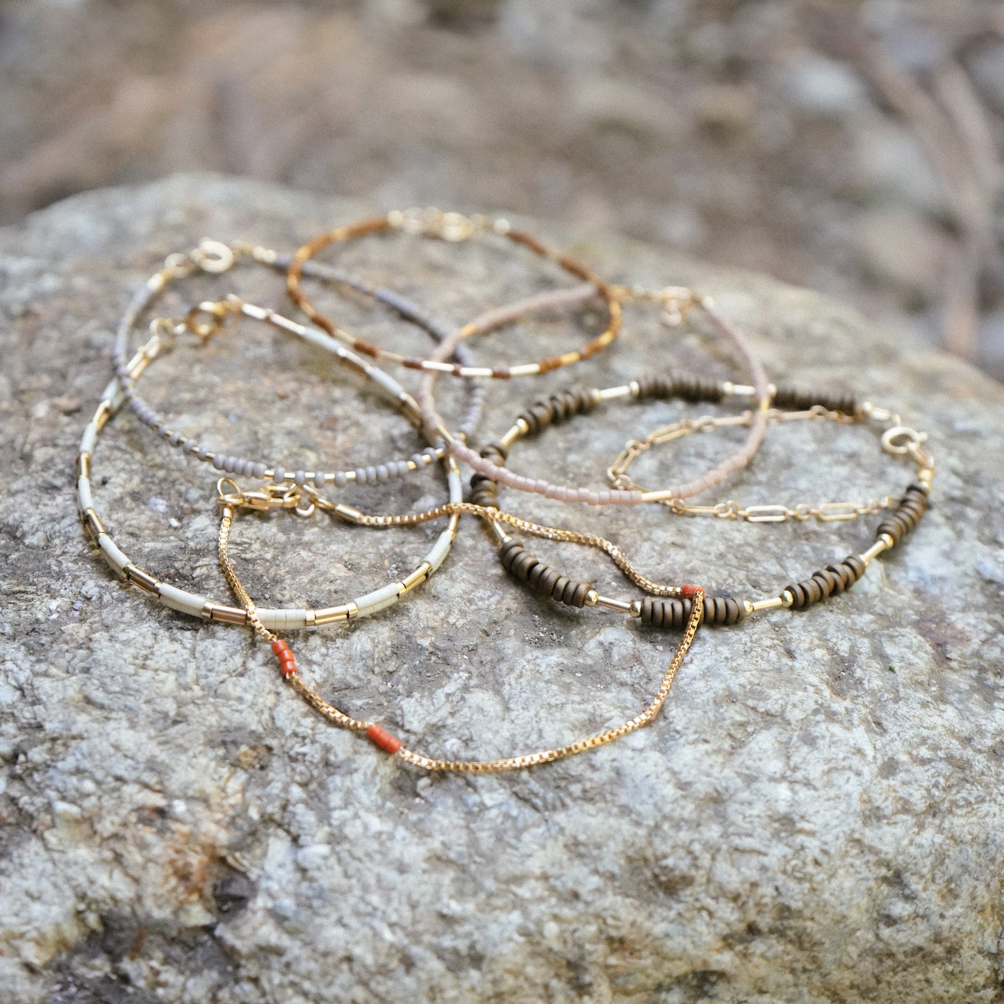 bundle of six beaded bracelets resting on a boulder