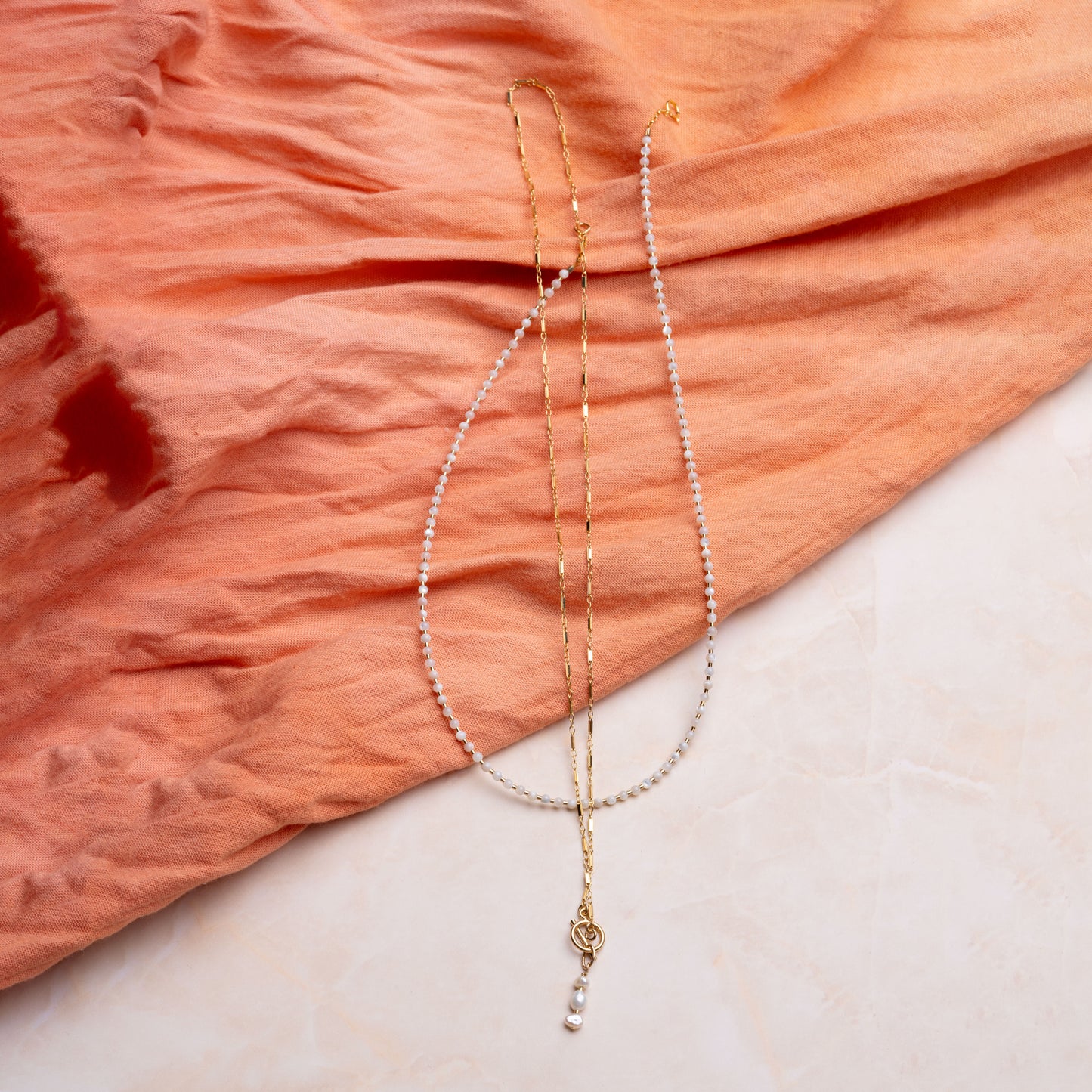 two necklaces with mother of pearl on a coral cloth