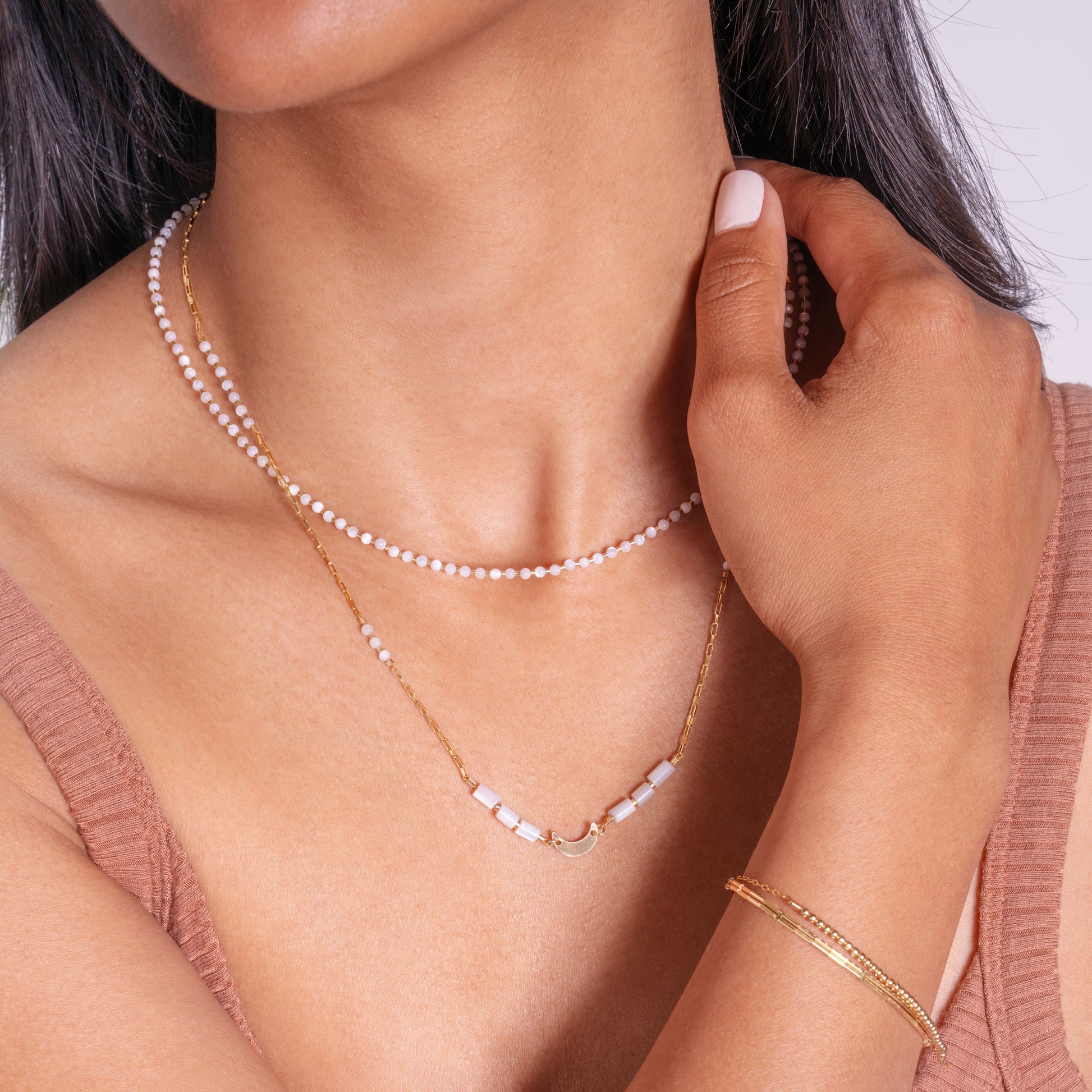 woman wearing two necklaces with mother of pearl beads and two gold-fill bracelets