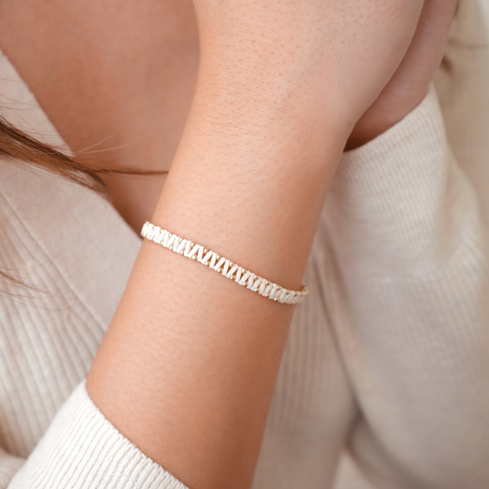 woman's wrist with bracelet with white Japanese glass and gold-fill ball beads
