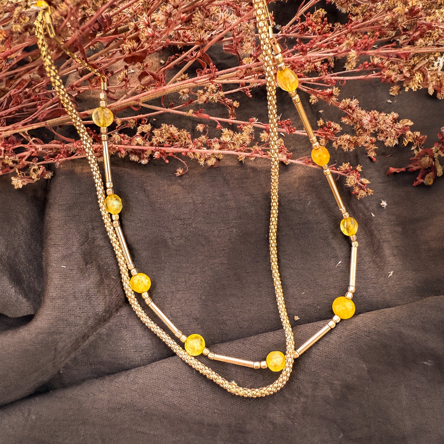 pair of necklaces with gold-filled beads and chains on a bouquet of dried flowers