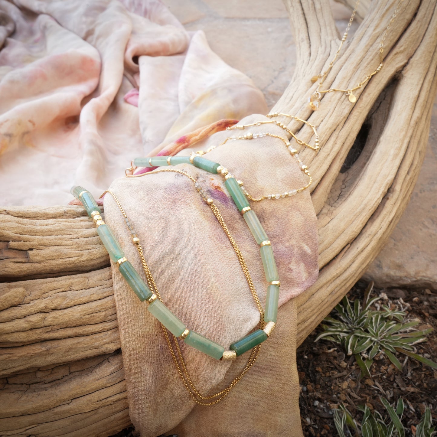 necklaces and bracelets on a scarf and wooden log