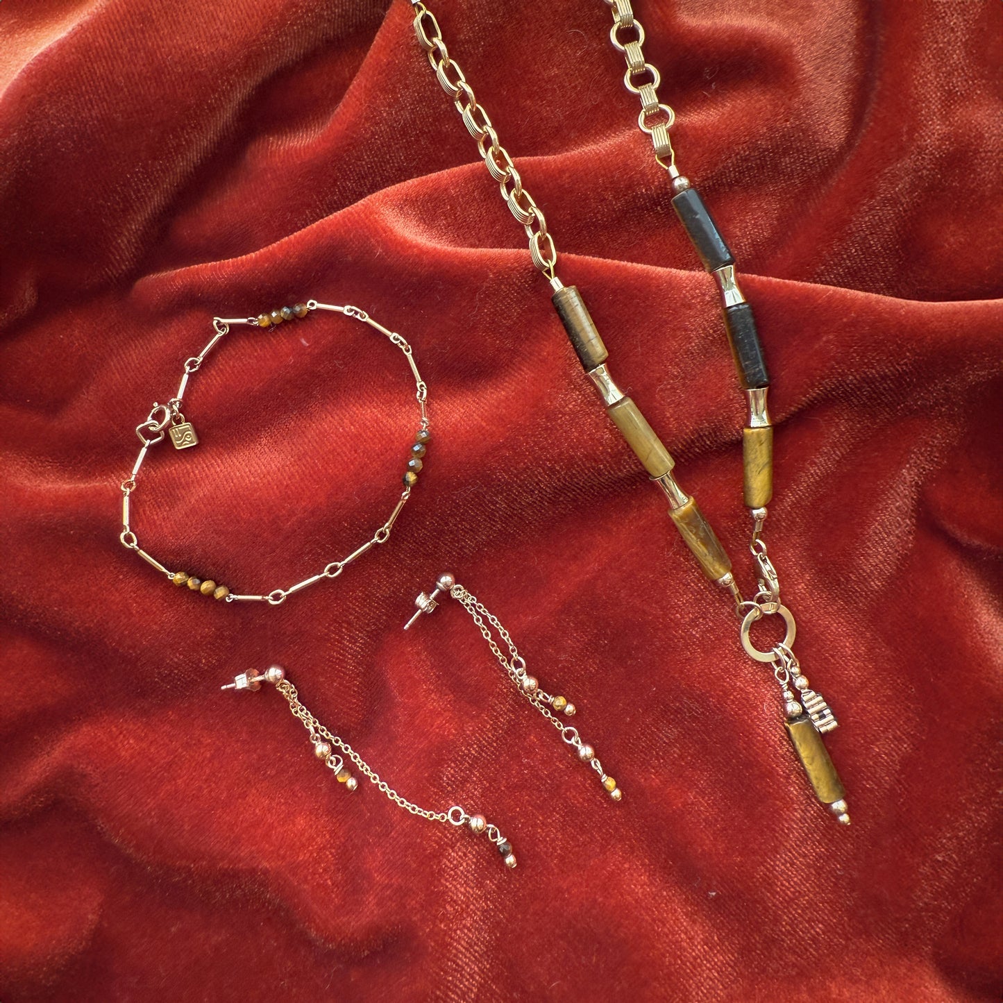 bundle of a necklace with tiger's eye beads and gold-filled beads, a bracelet with tiger's eye and gold-filled beads, and a pair of earrings with dangling chains containing tiger's eye and gold-filled beads