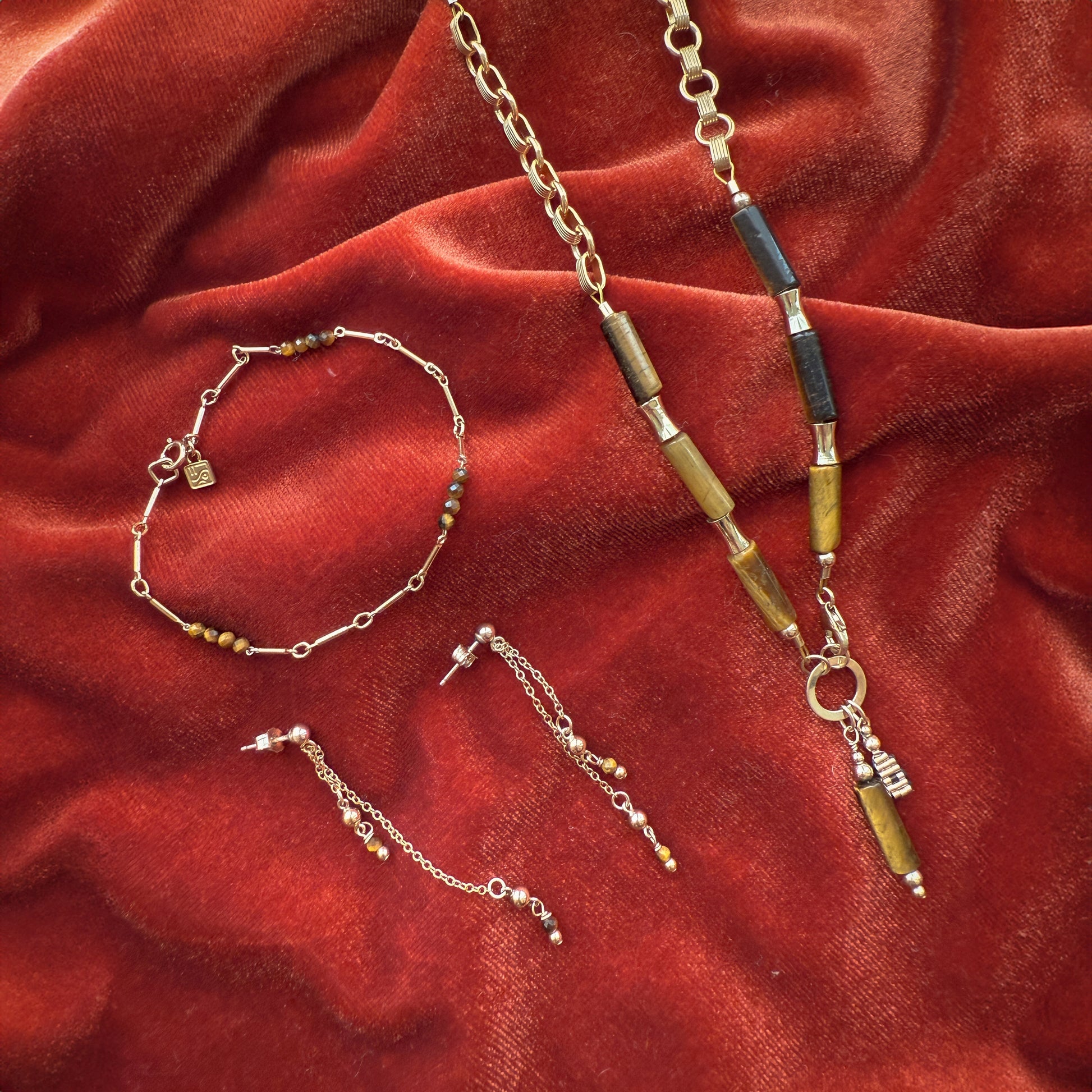 bundle of a necklace with tiger's eye beads and gold-filled beads, a bracelet with tiger's eye and gold-filled beads, and a pair of earrings with dangling chains containing tiger's eye and gold-filled beads