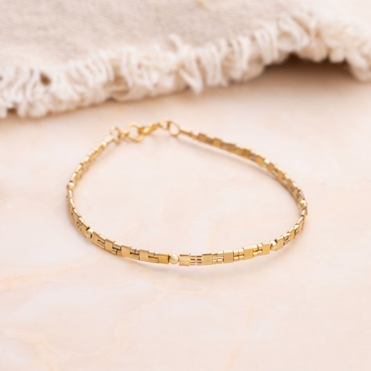patterned gold-filled bead bracelet with rug in the background