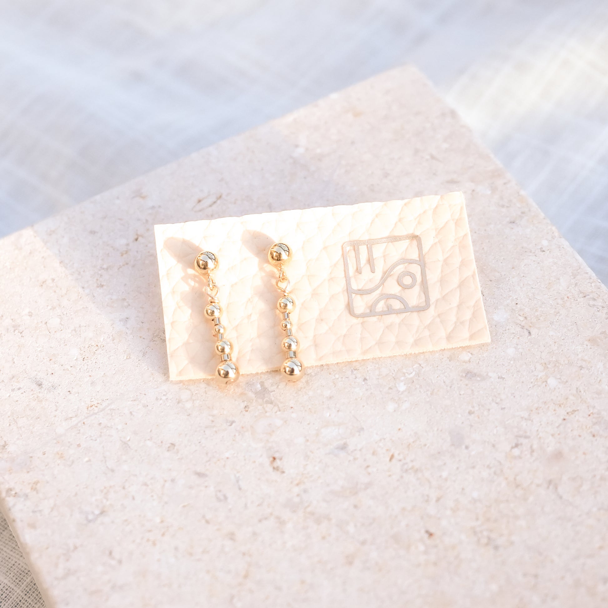 14k gold-fill beaded earrings on a piece of faux leather with the so niice logo