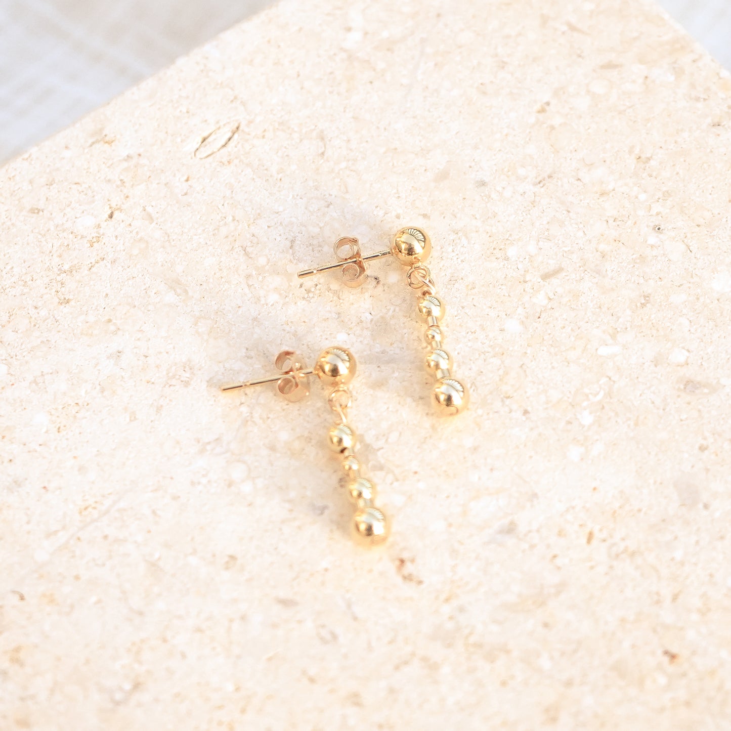 14k gold-fill beaded earrings on a stone background