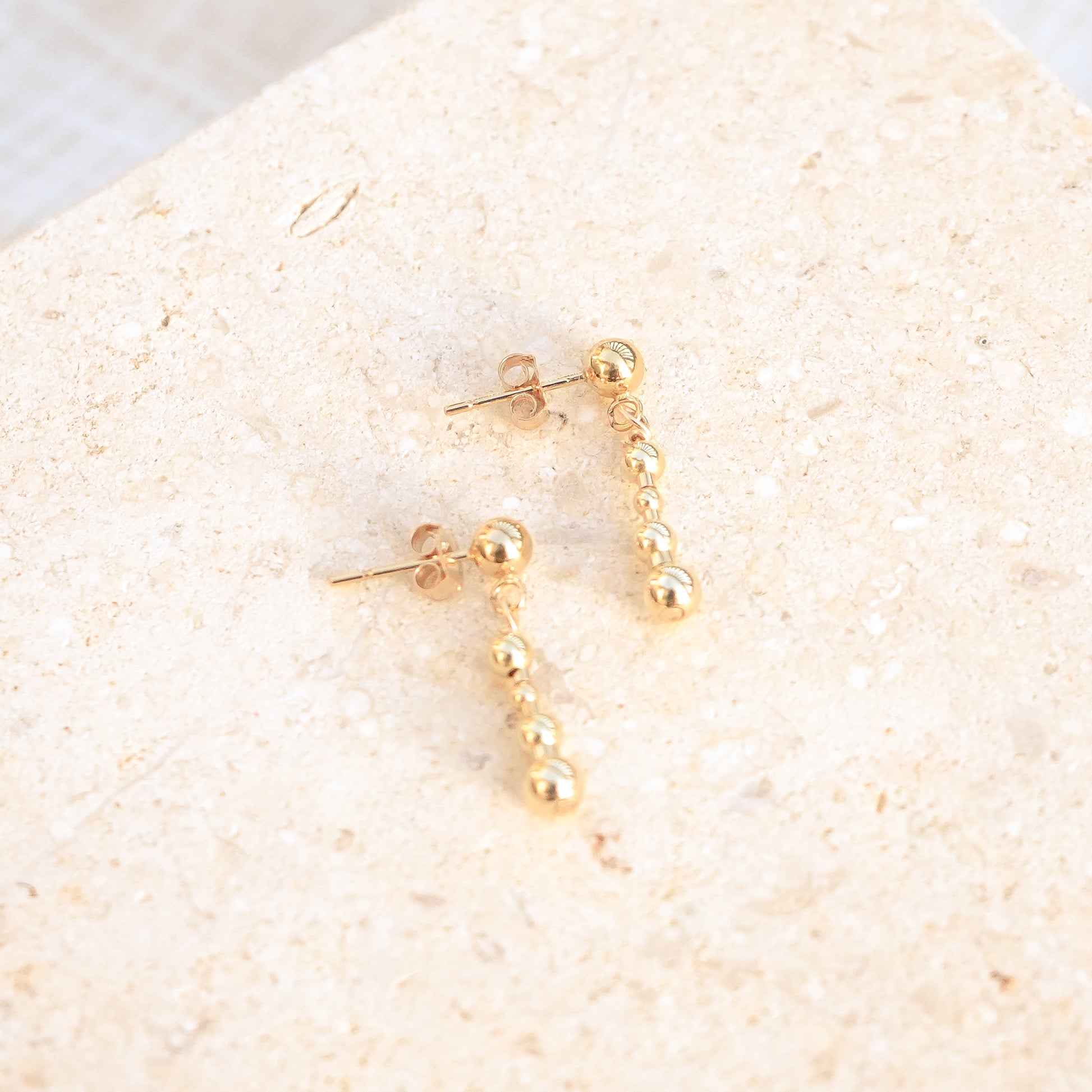 14k gold-fill beaded earrings on a stone background