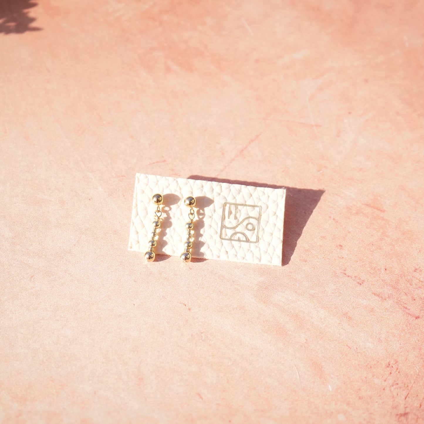 14k gold-fill beaded earrings on a piece of material with the so niice logo