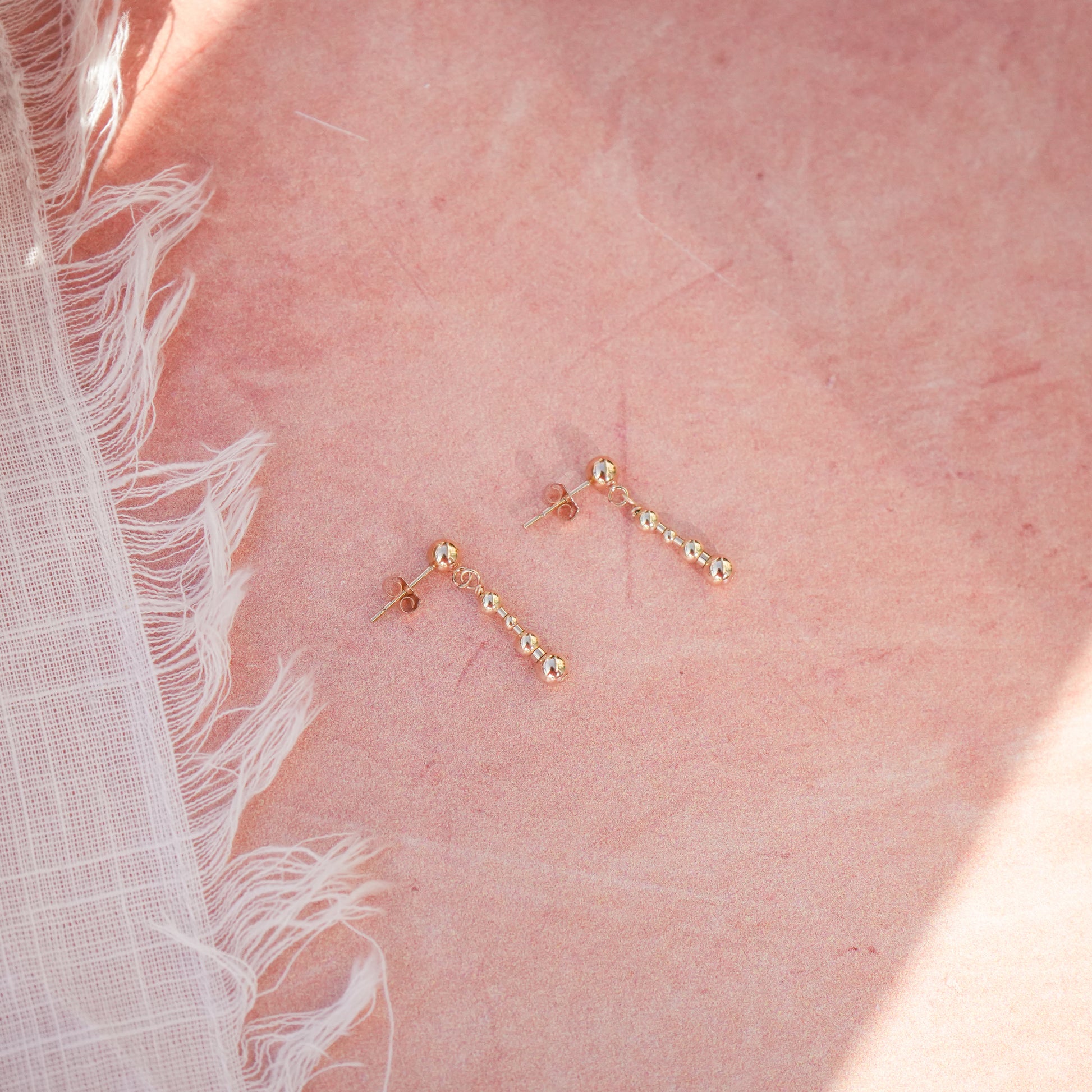 pair of 14k gold-fill beaded earrings next to a white cloth