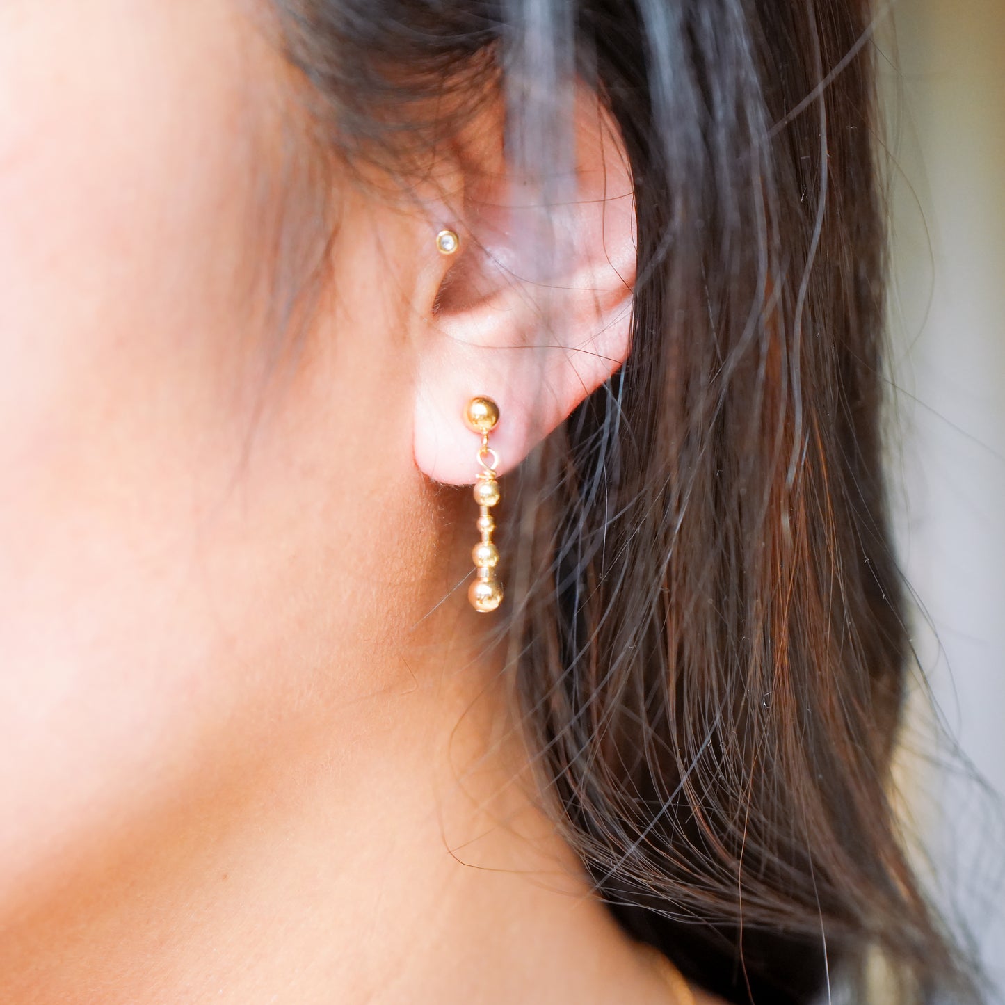 woman's ear wearing a 14k gold-fill beaded earring