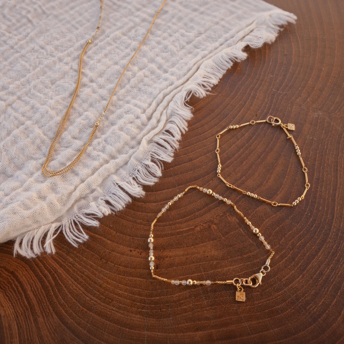 two bracelets and a necklace with gold-fill chain and citrine faceted stones on a white cloth
