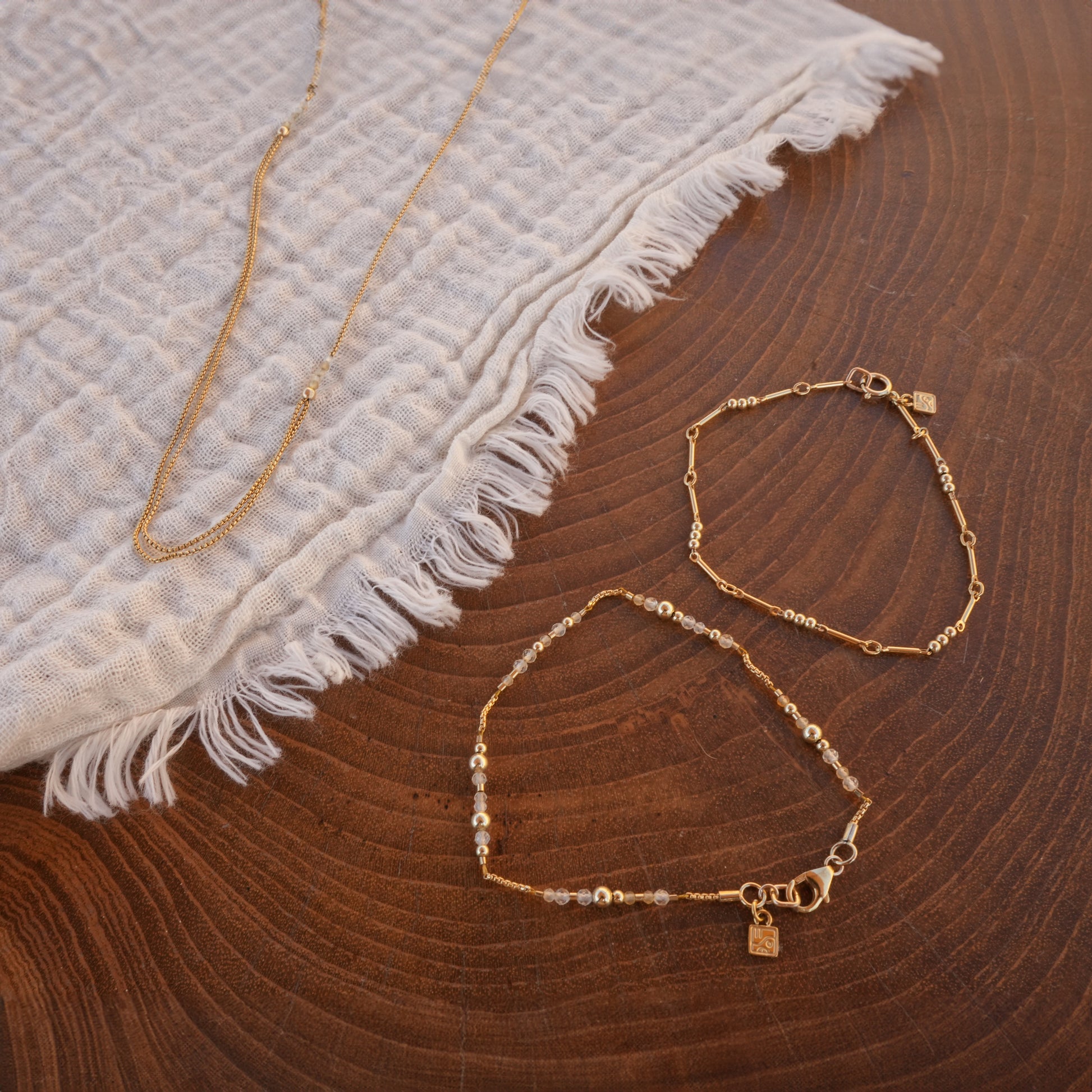 two bracelets and a necklace with gold-fill chain and citrine faceted stones on a white cloth